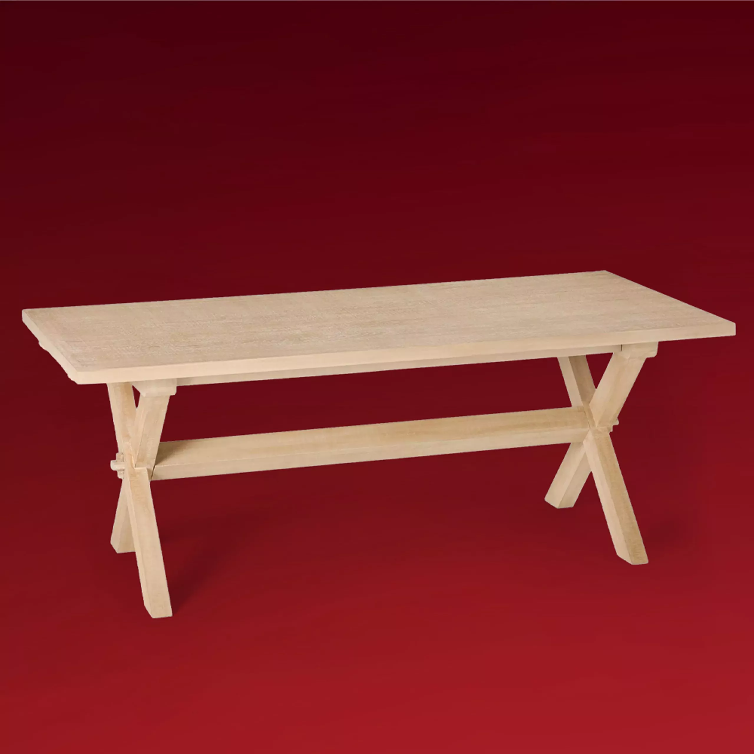 Light oak trestle dining table with cross legs and stretcher rail, photographed against a deep red backdrop