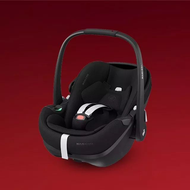 Maxi-Cosi black infant car seat carrier with safety harness and canopy, isolated on red background