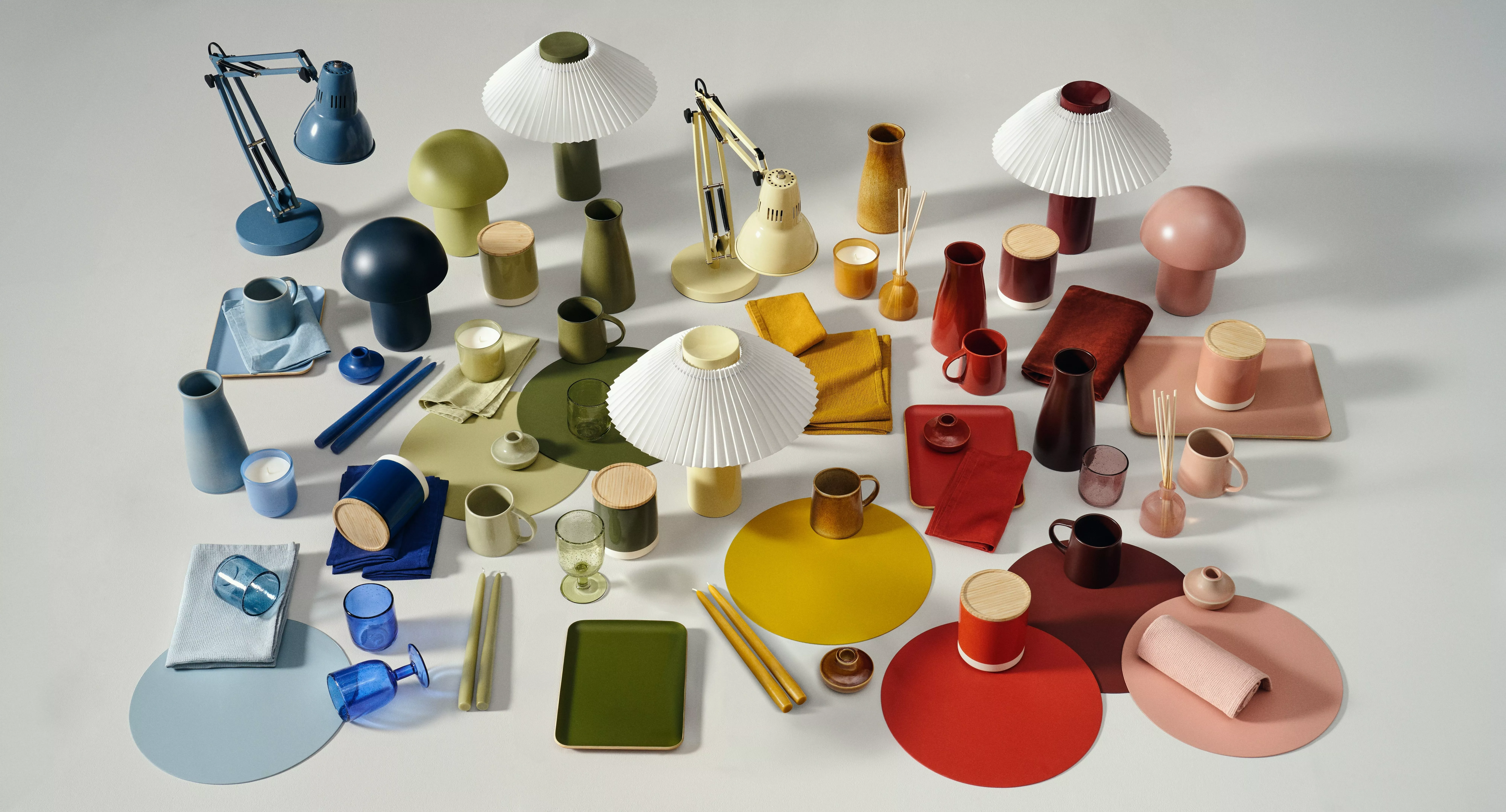 Colourful modern homeware flat lay with lamps, mugs, vases, trays and textiles in a curated studio setting