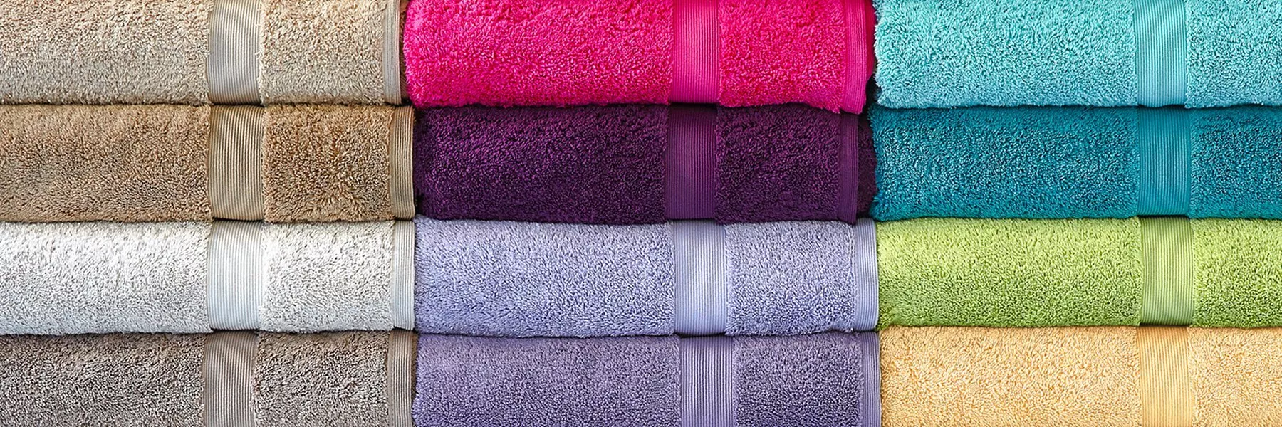 Stack of colourful folded bath towels in assorted shades, neatly arranged for bathroom linen and home décor