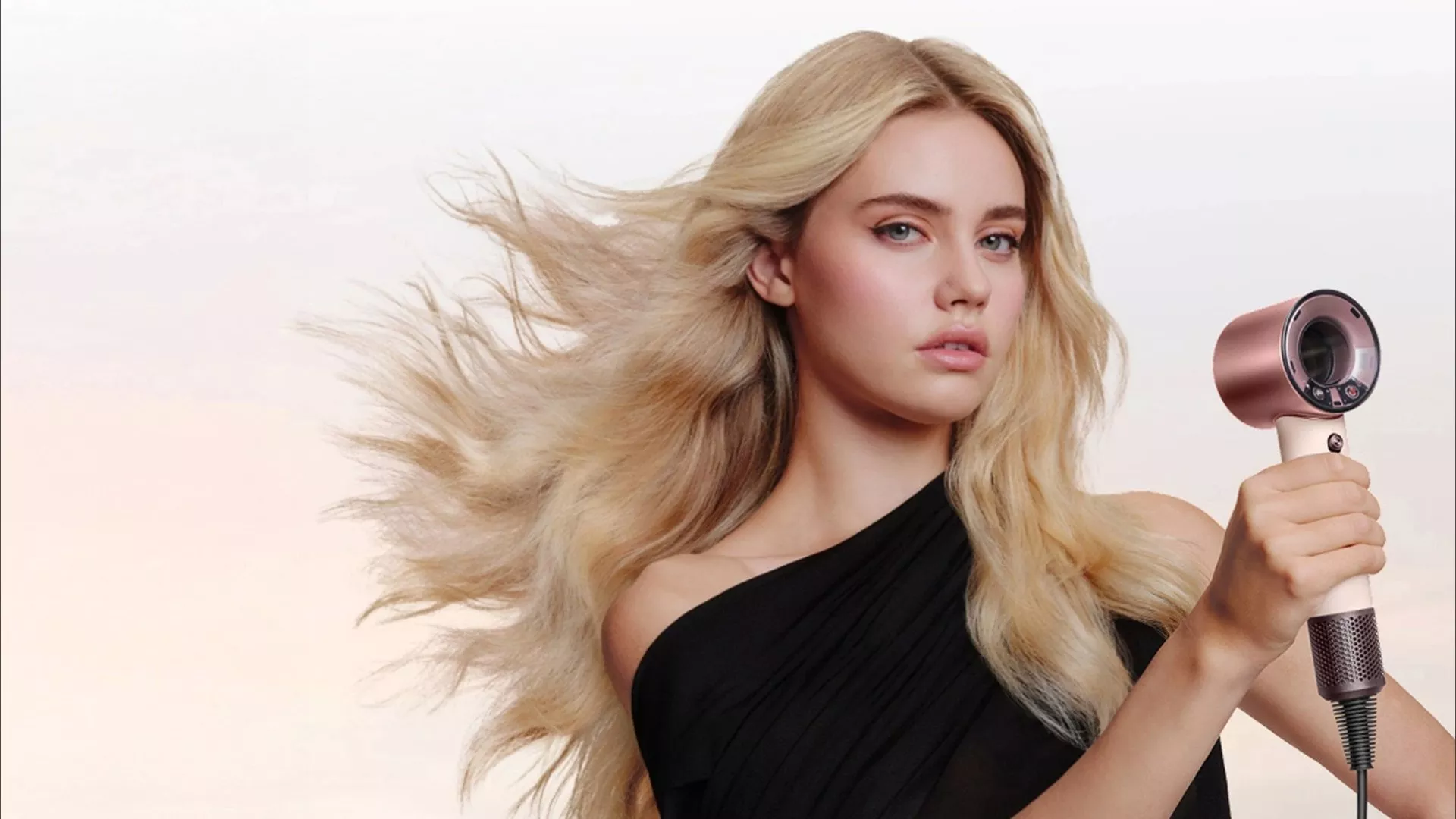 Blonde woman with flowing hair holding a rose gold hair dryer, showcasing fast drying and smooth styling results