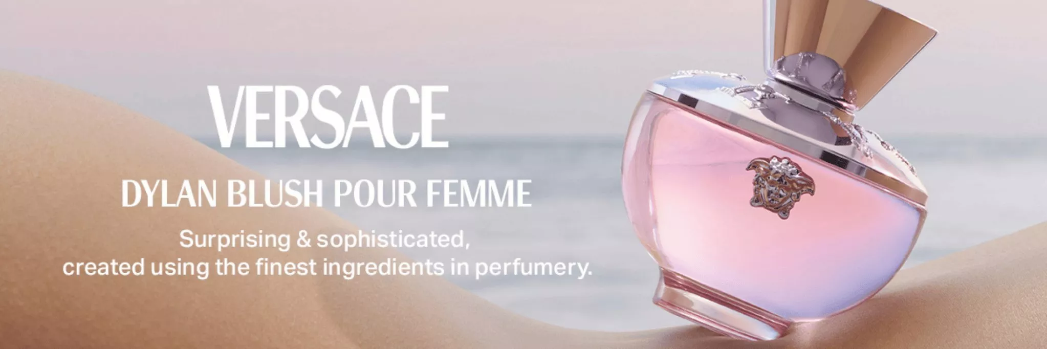 This is a banner for Versace showing a fragrance lying in the sand.