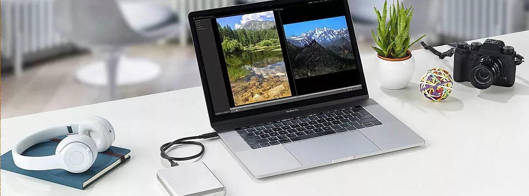 Laptop on wooden desk with external hard drive, coffee cup, wallet and keys, ideal home office setup