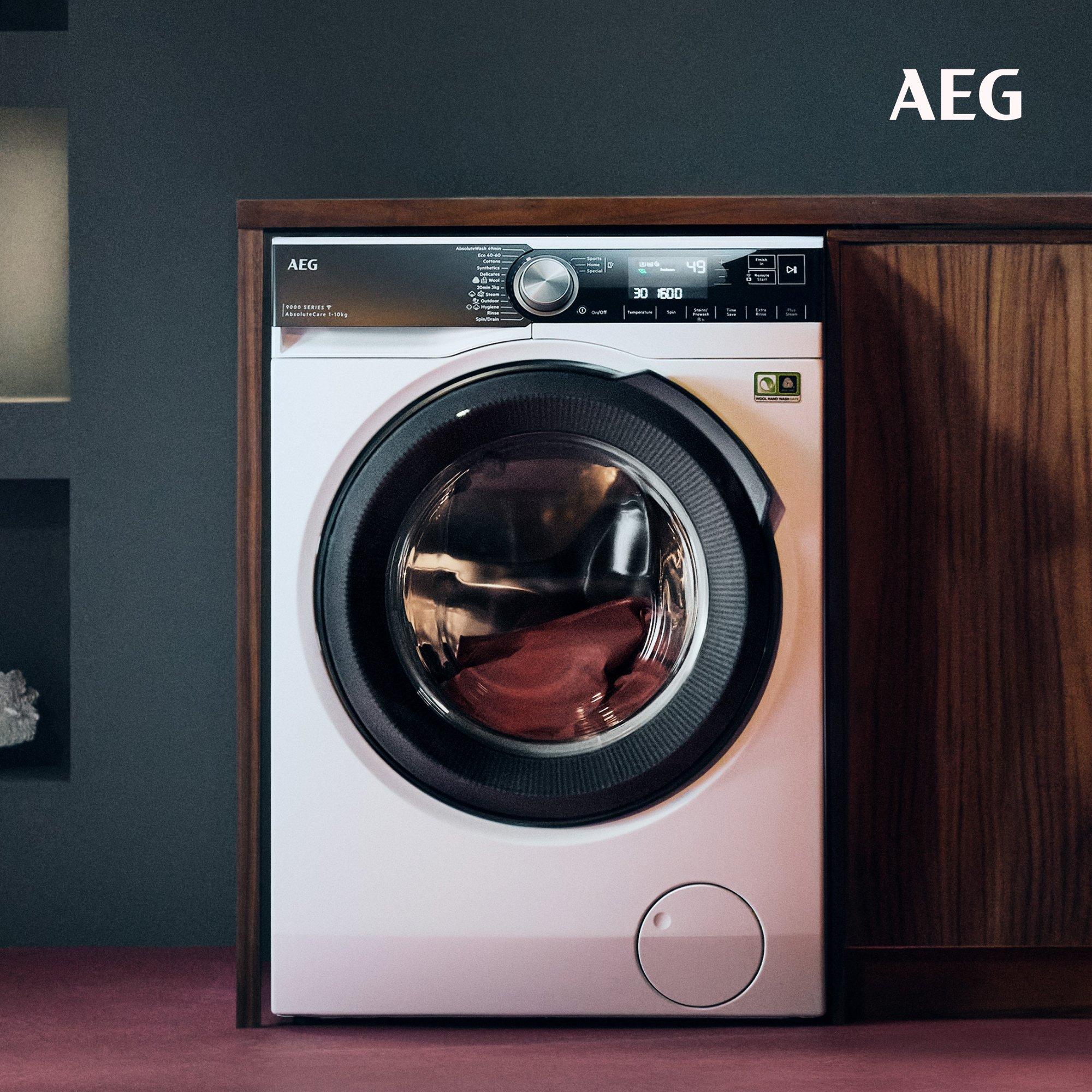 Front-loading AEG washing machine built into a wooden cabinet, with a sleek digital control panel