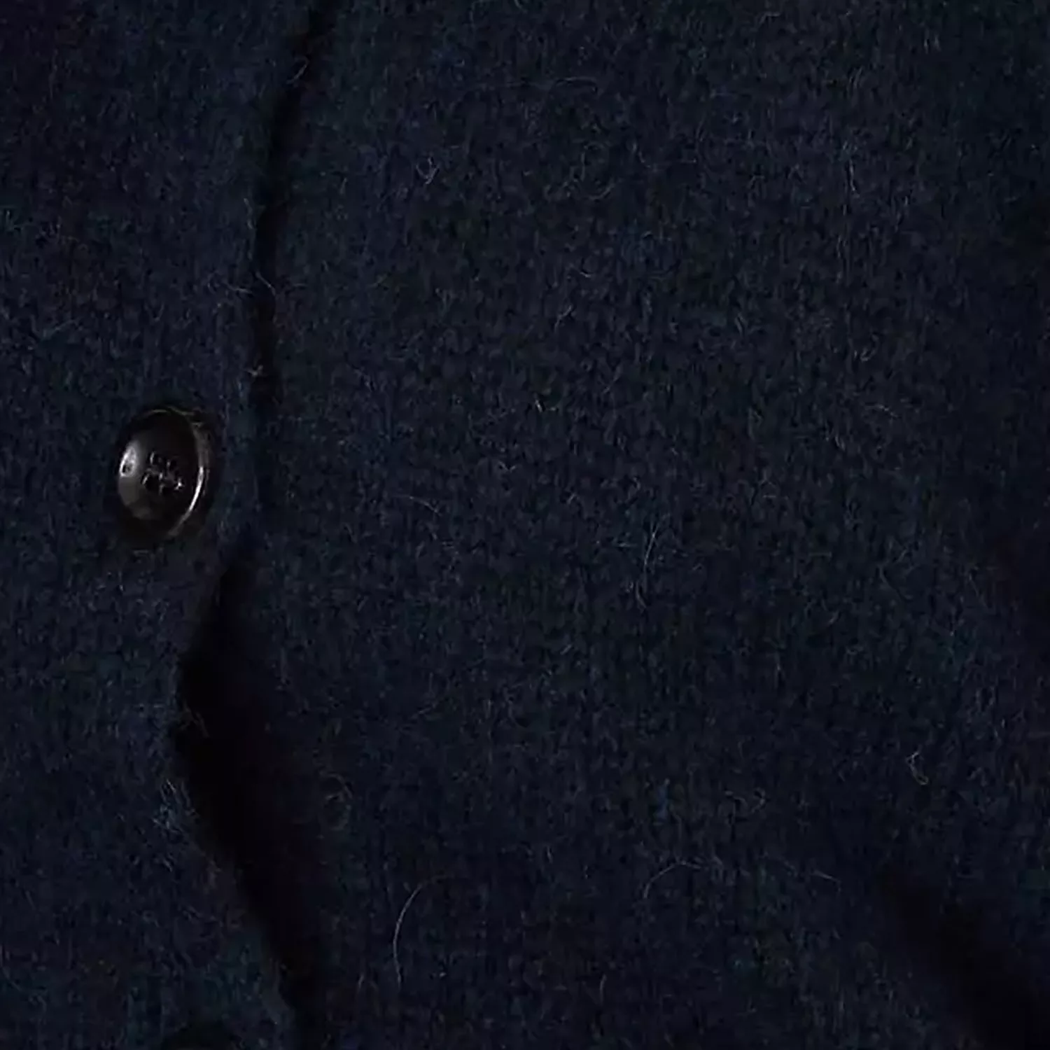 Close-up of navy wool coat fabric with button detail, showing warm winter outerwear texture and stitching