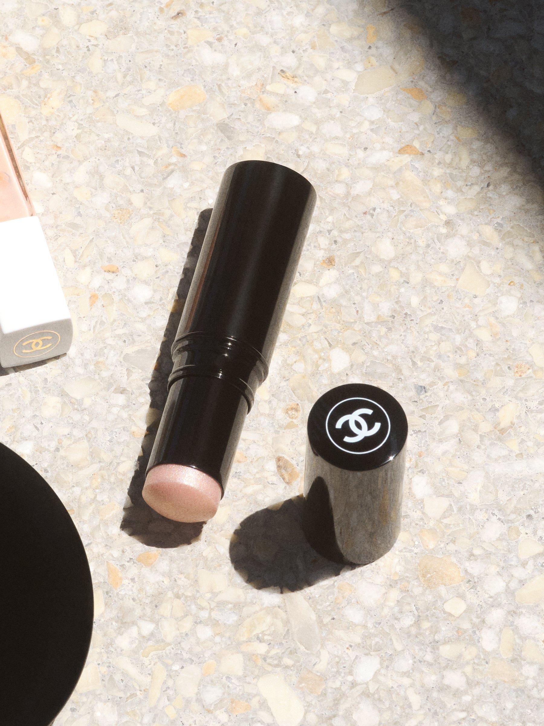 Image of a the CHANEL Baume Essentiel Multi-Use Glow Stick sitting on a step in the sun