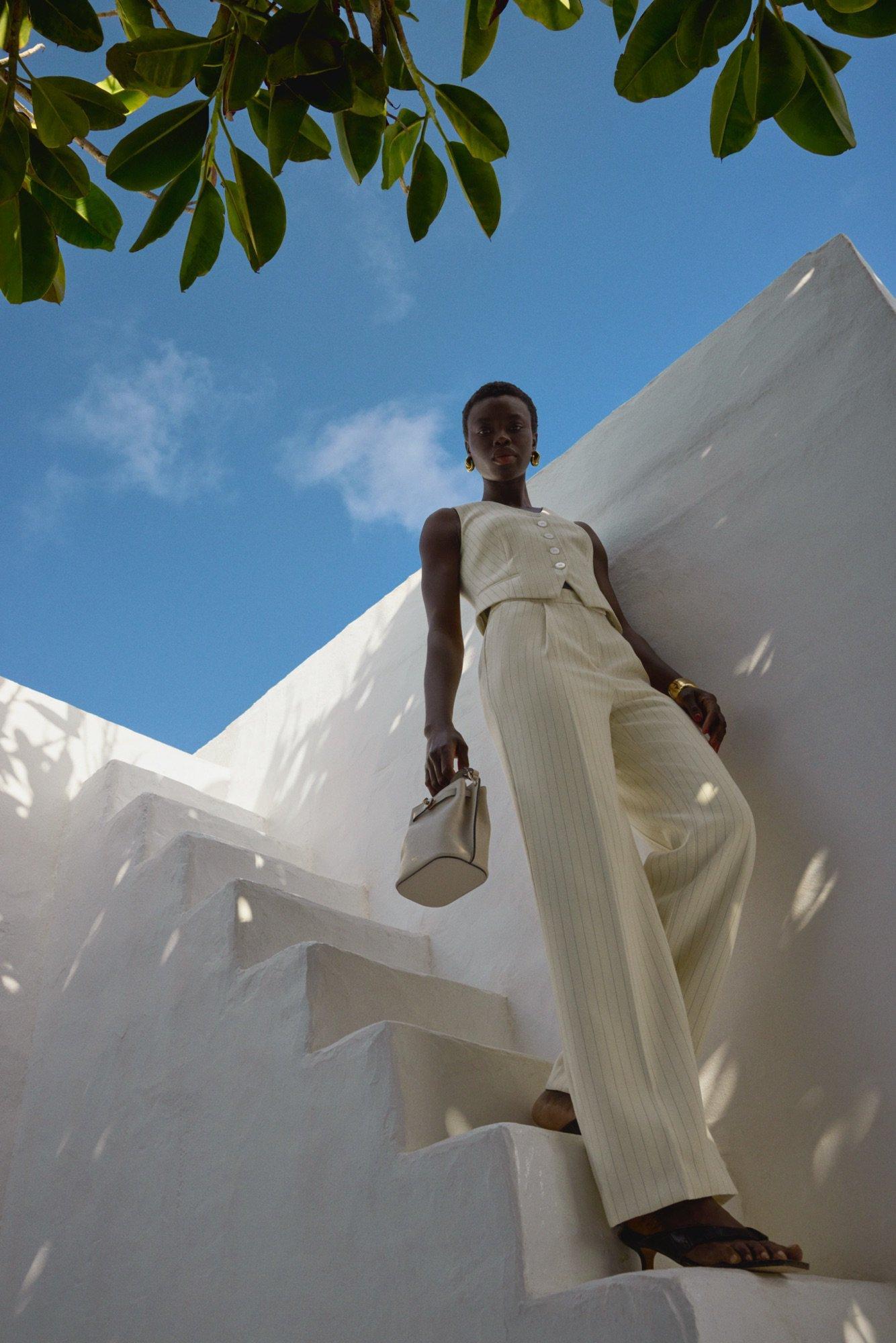 A lady walking down outdoor stairs wearing a crop top cream suit