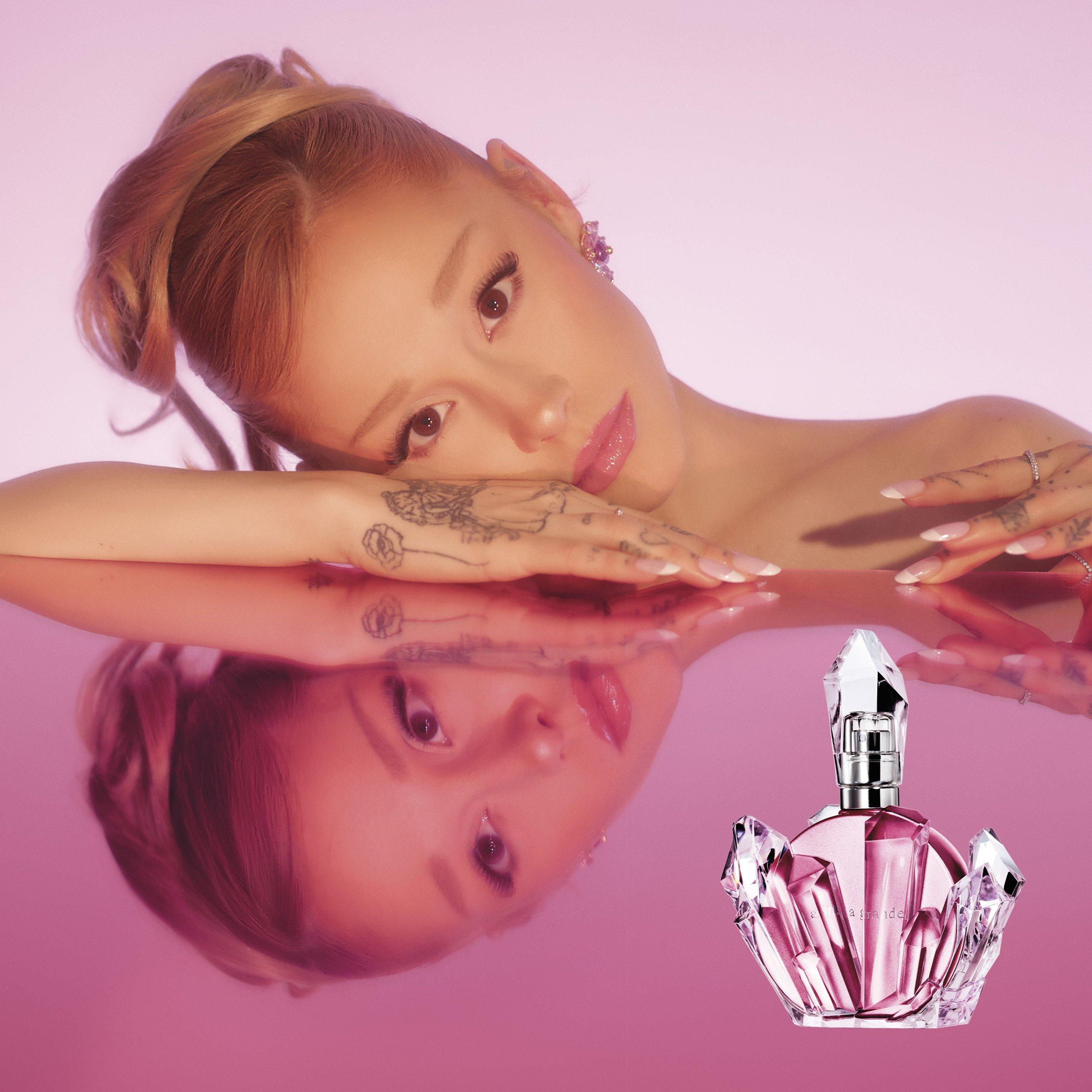 ariana grande on pink glassy table with her perfume brand