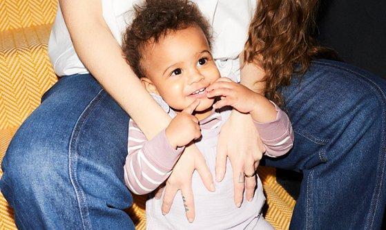 Image of a baby leaning up against it's mother, they are both sitting on the stairs