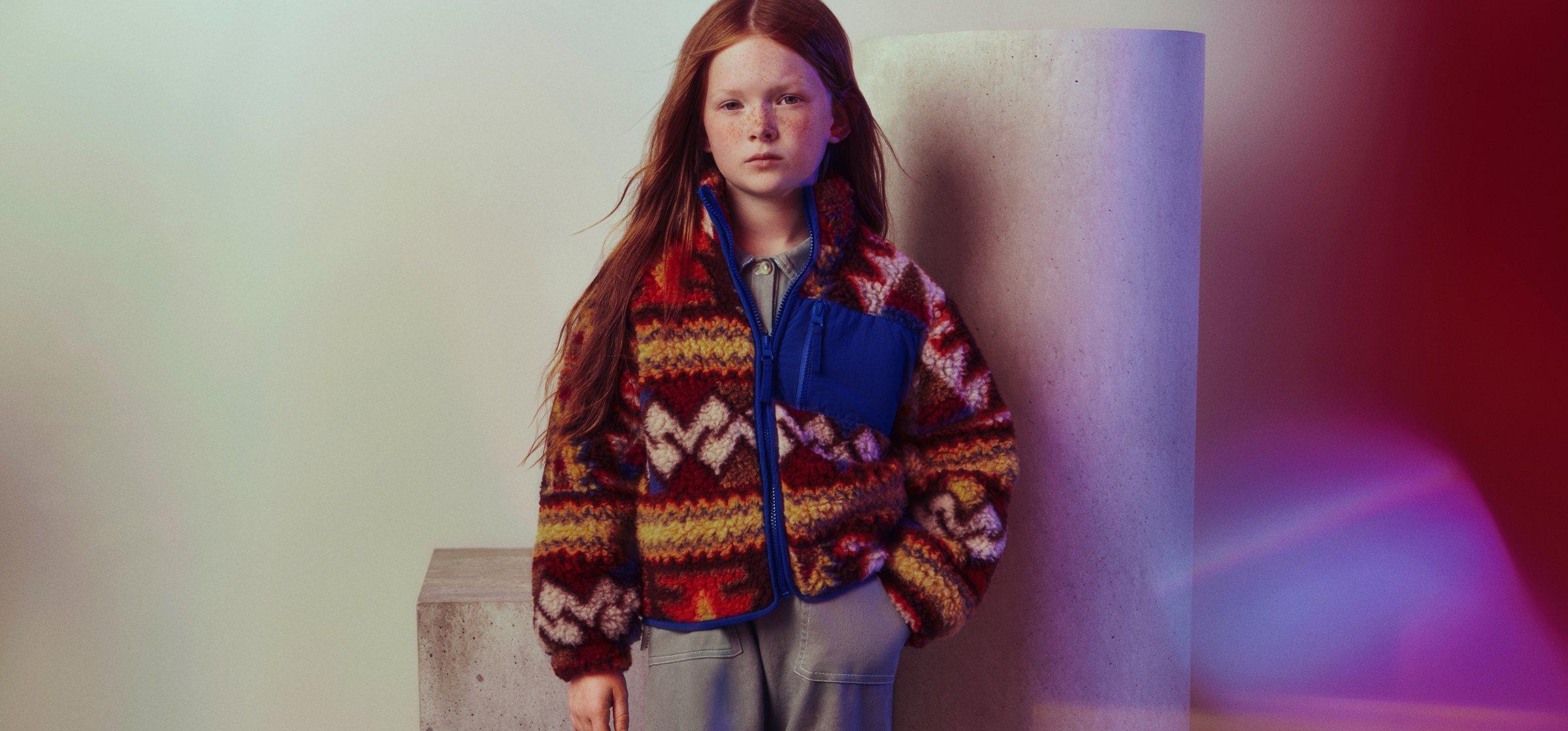 a girl wearing a multi-coloured jacket by The New Society
