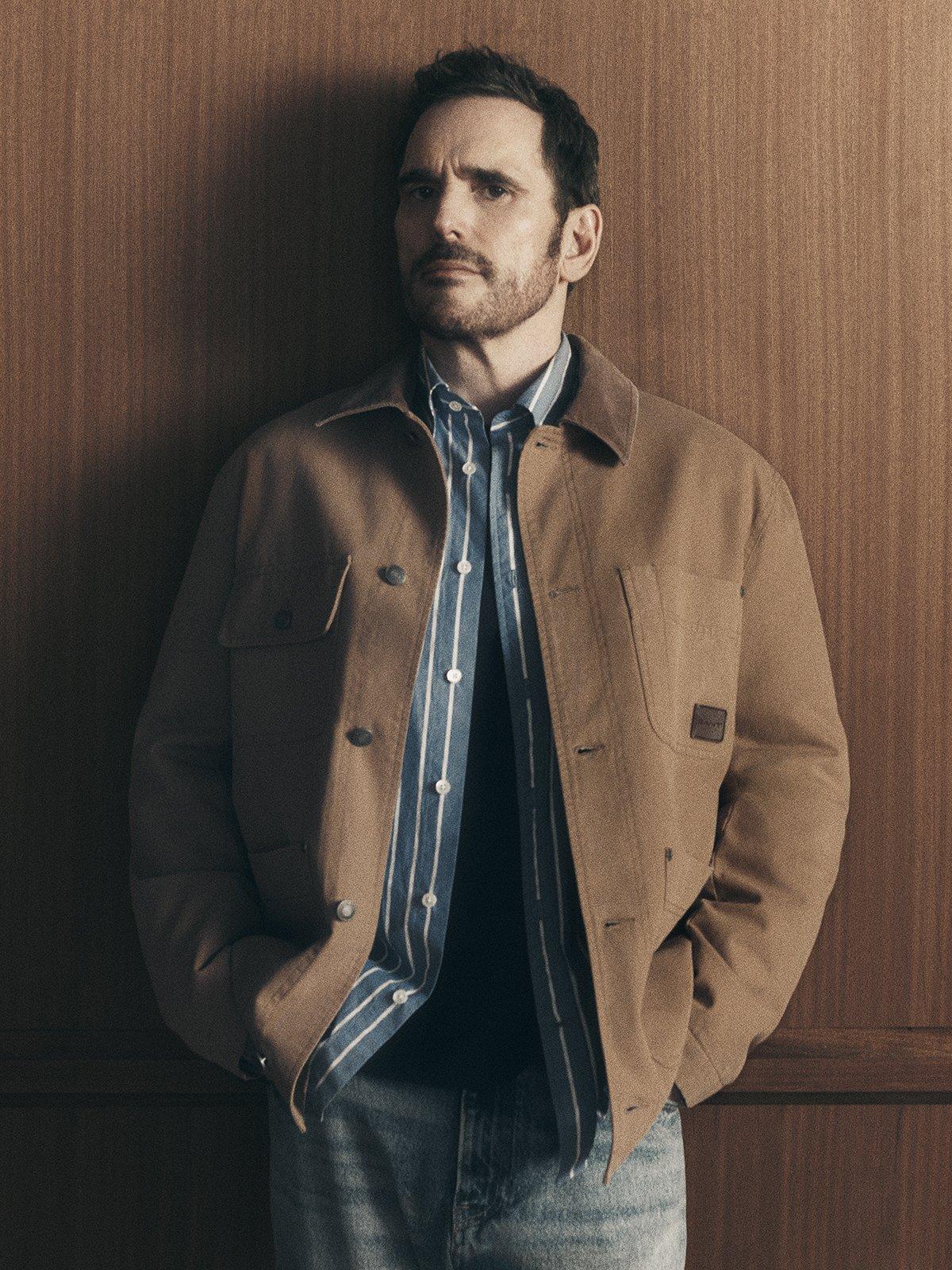 Make model wearing blue and white sriped shirt and light brown shacket