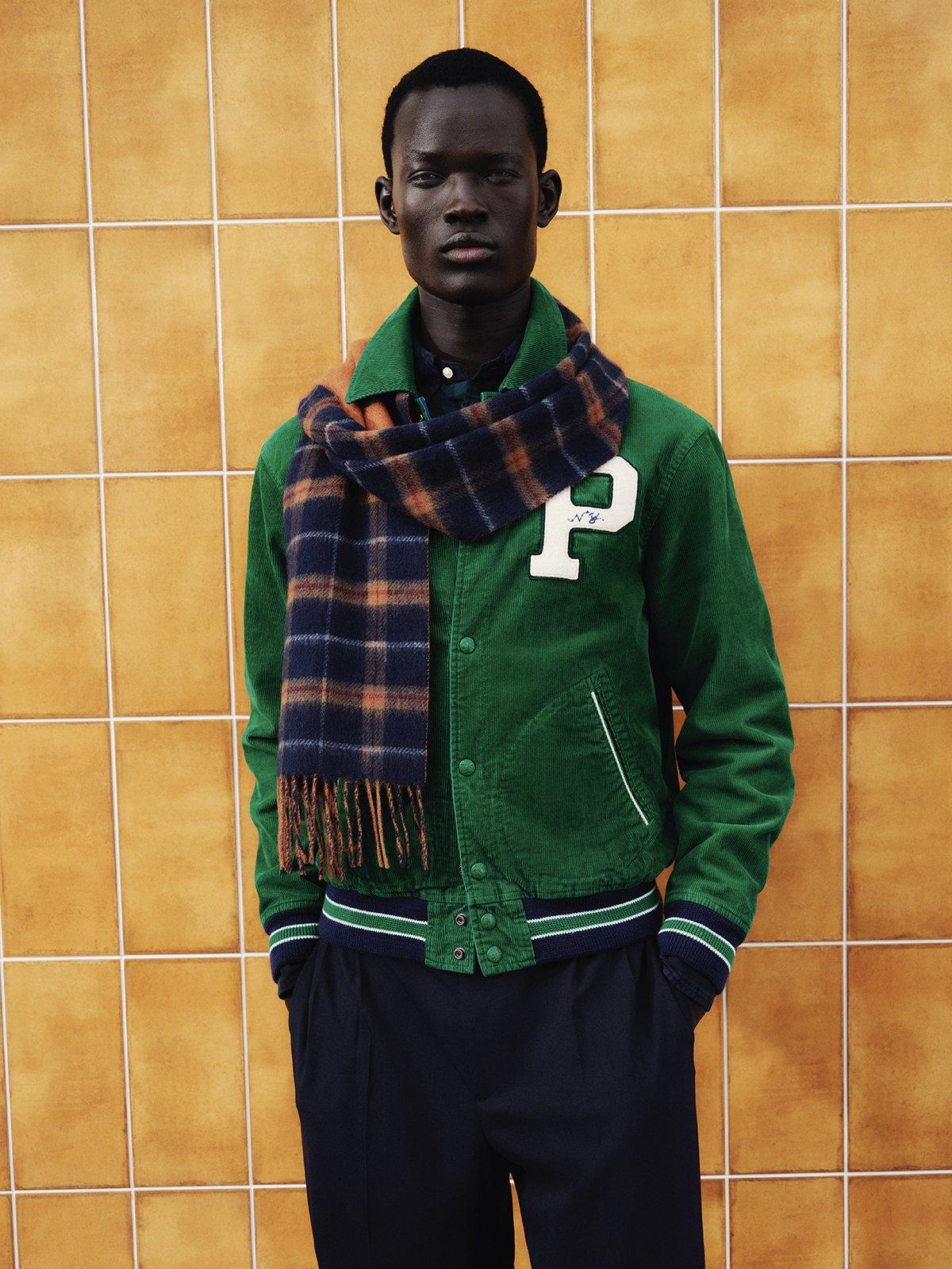Male model wearing green bomber jacket and blue and orange checkered scarf