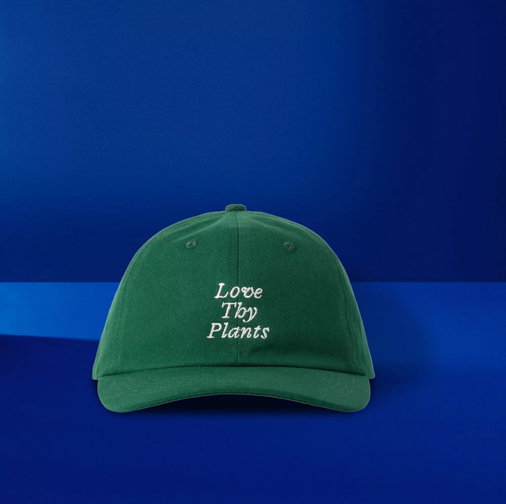 Green embroidered baseball cap with “Love Thy Plants” slogan on blue background