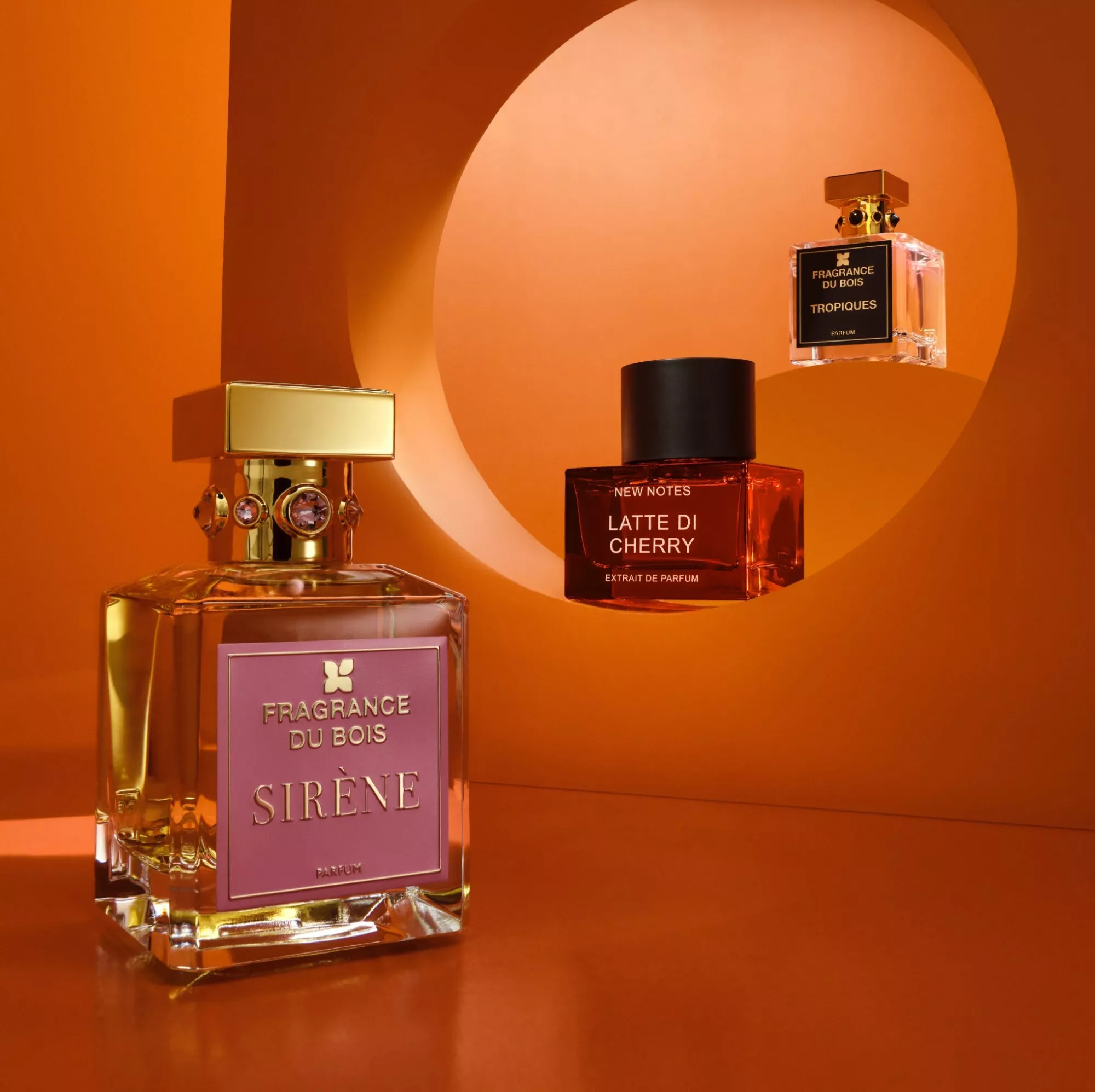 Luxury perfume bottles in orange studio display, including Fragrance Du Bois Sirène and New Notes Latte Di Cherry
