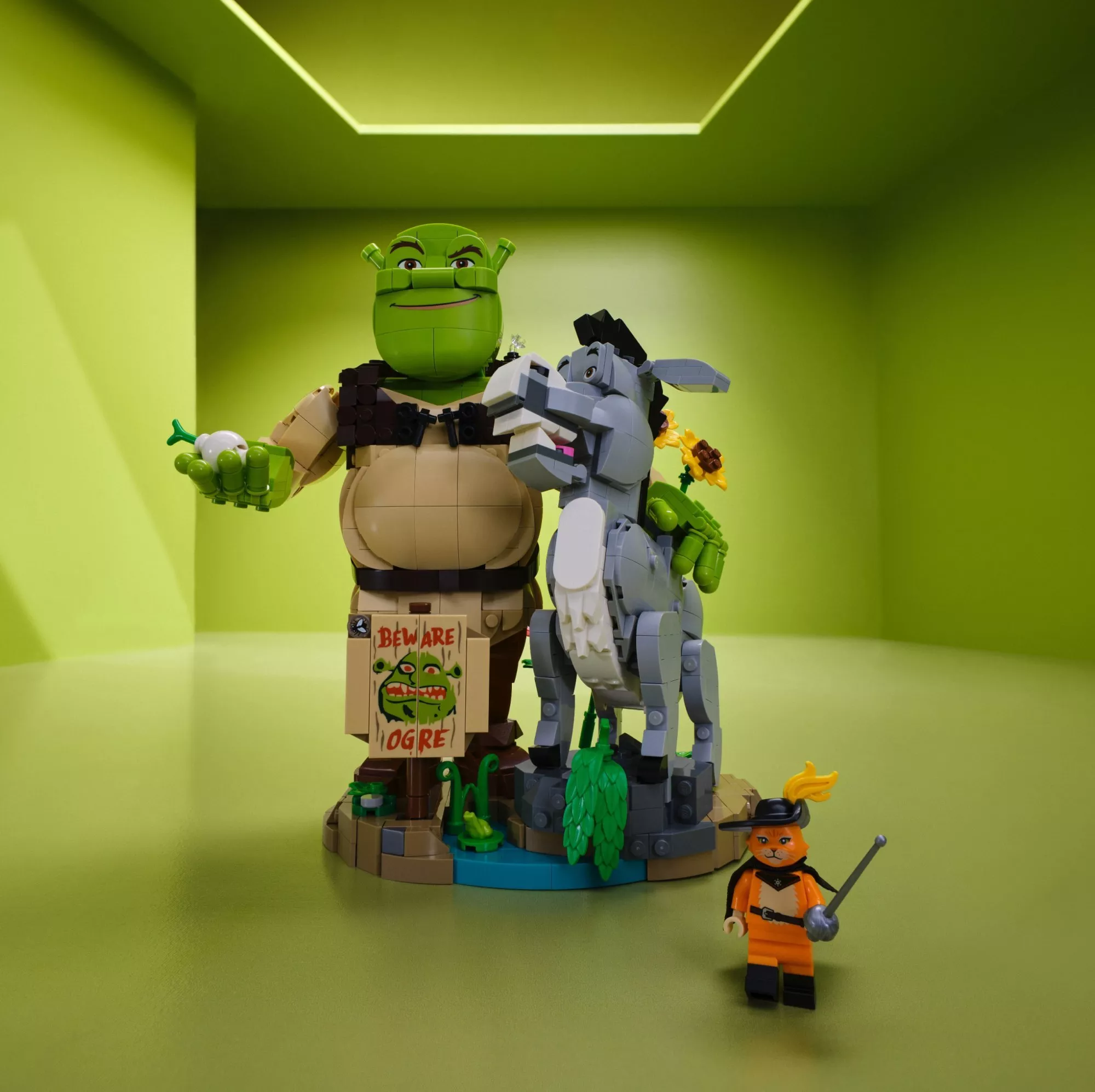 LEGO Shrek display with Donkey and Puss in Boots minifigure in green room, “Beware Ogre” sign visible