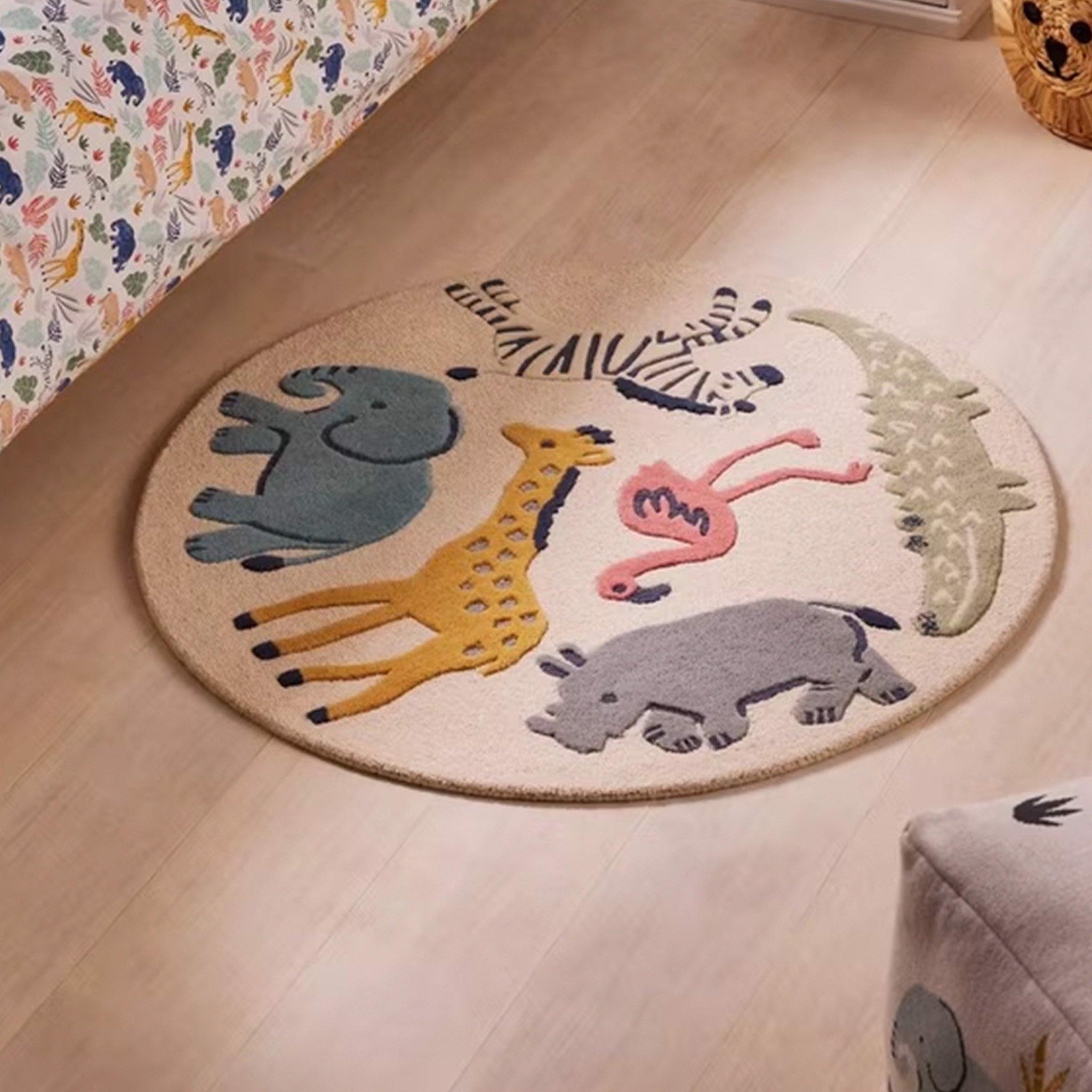 The image shows a round nursery rug featuring colorful animal illustrations, including an elephant, giraffe, zebra, flamingo, crocodile, and rhino, on a light background.