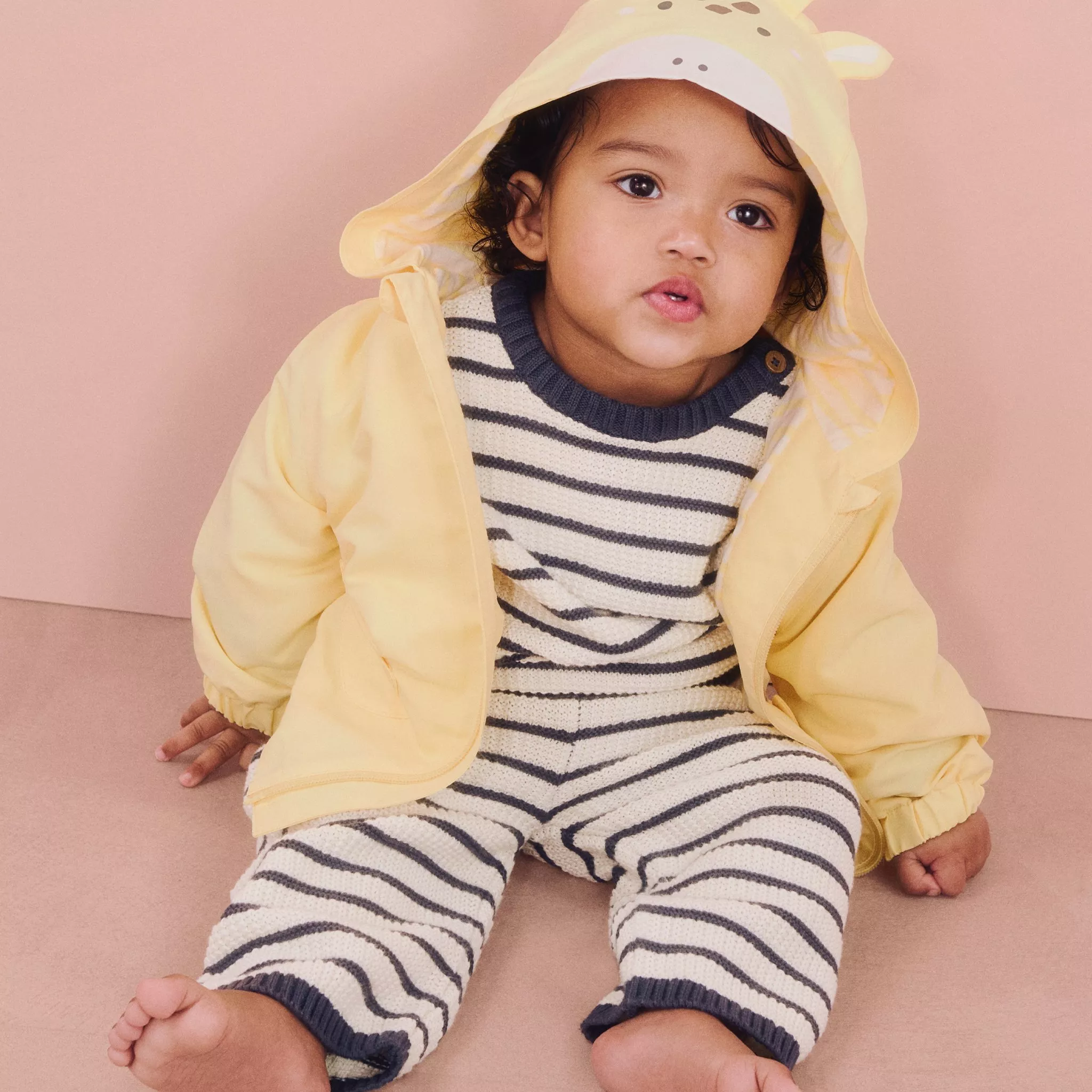 baby in stripe outfit and yellow jacket