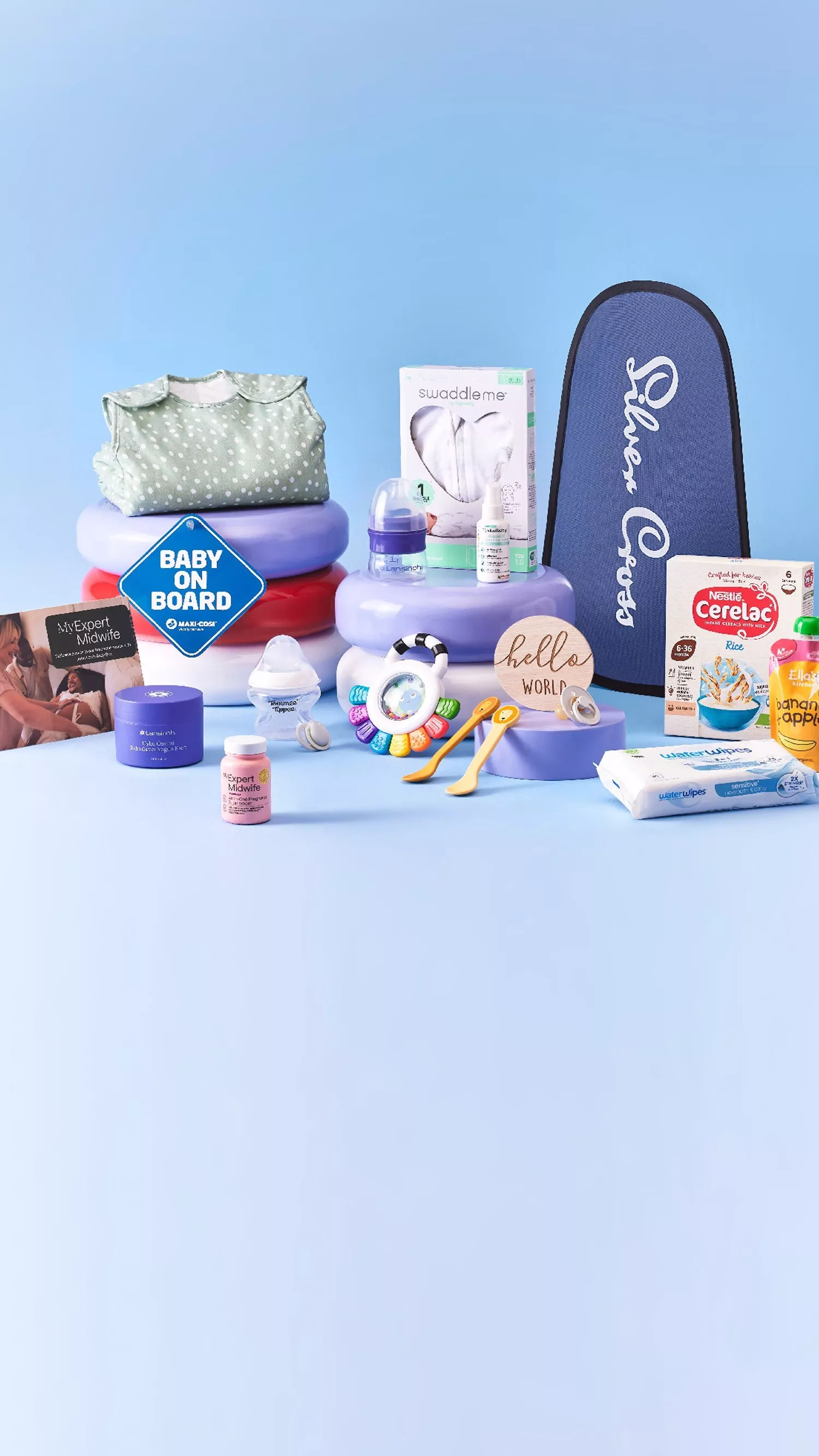 New baby essentials hamper: swaddle, bottles, wipes, baby food, toys and Baby on Board sign on blue backdrop