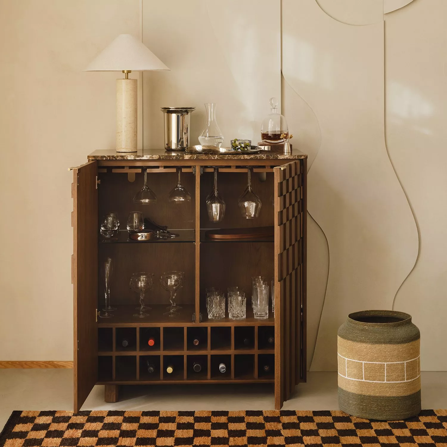 Mid-century walnut home bar cabinet with glassware, wine rack, marble top and table lamp in neutral room
