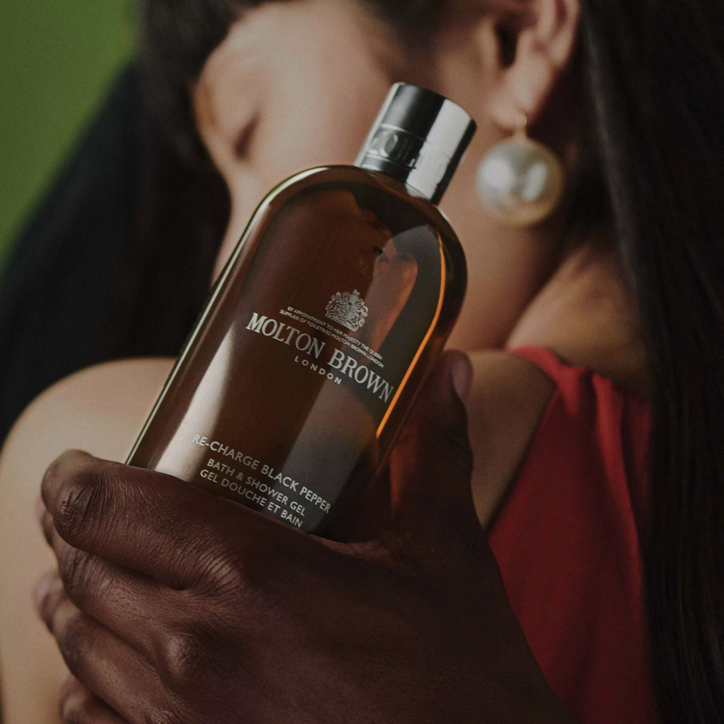 single molton brown shower gel being held in front of a person
