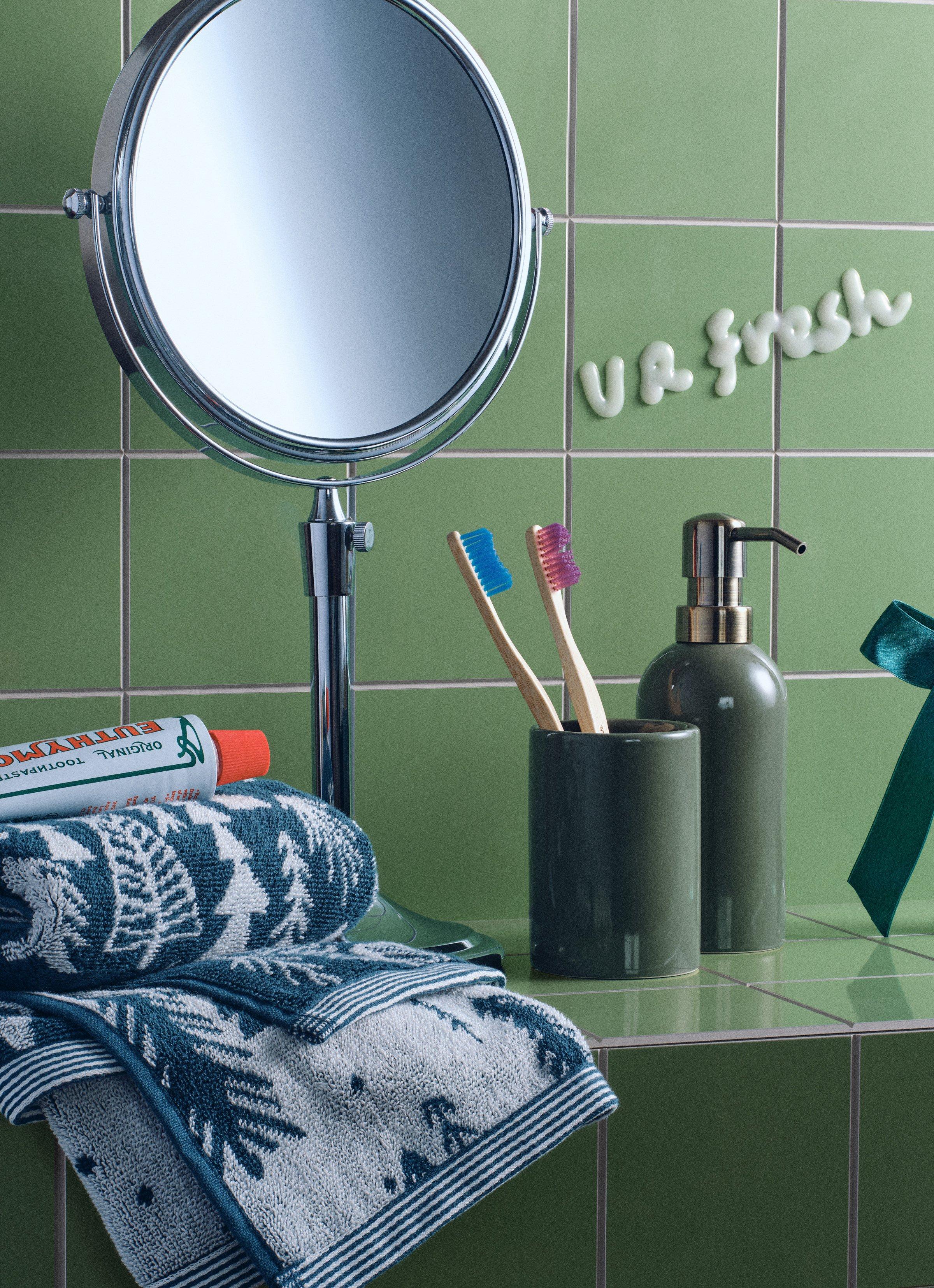 Bathroom accessories sitting on a green tiled shelf