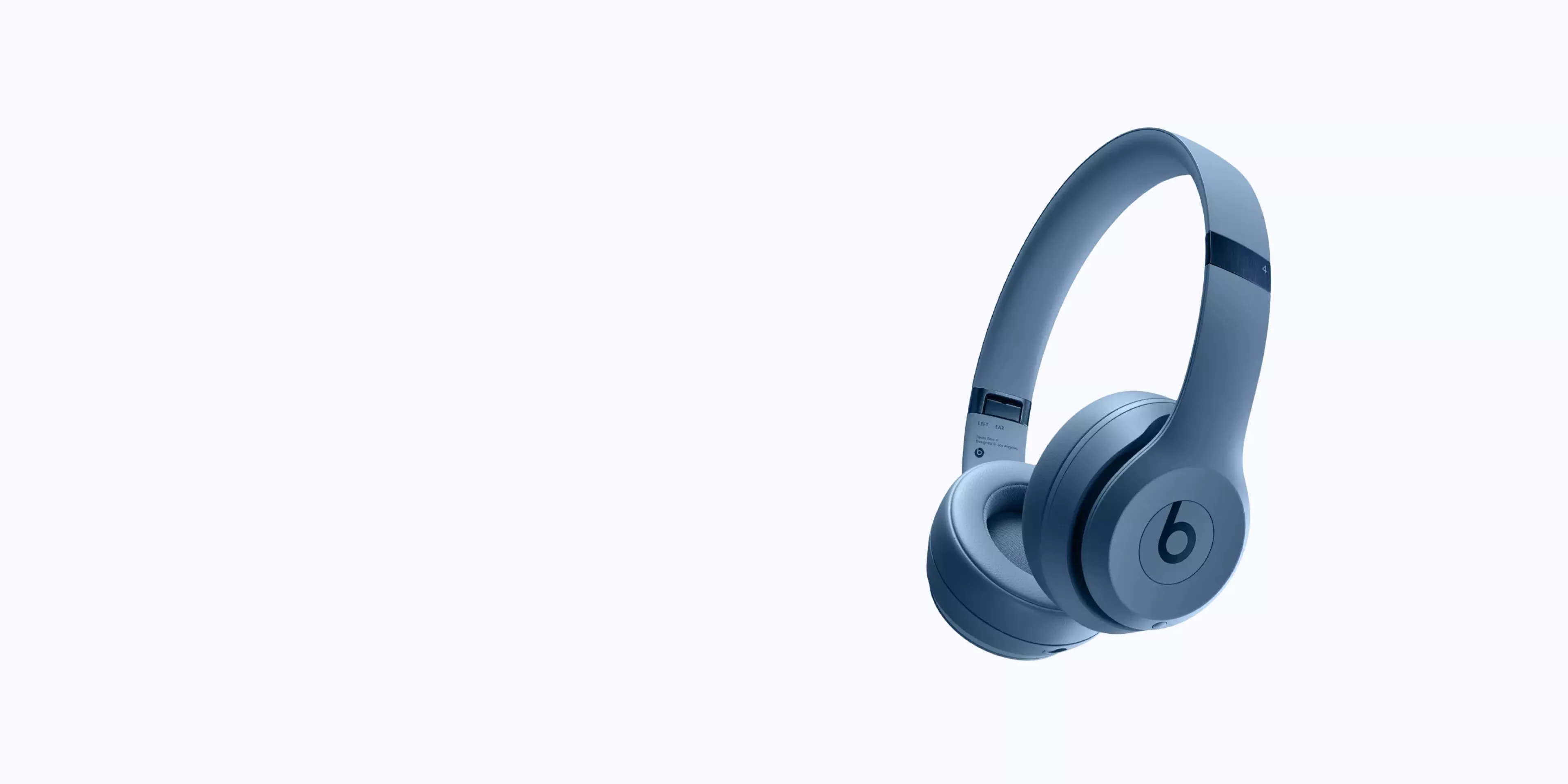 Blue Beats over-ear wireless headphones with cushioned ear cups, studio-style design, on a clean pale blue background