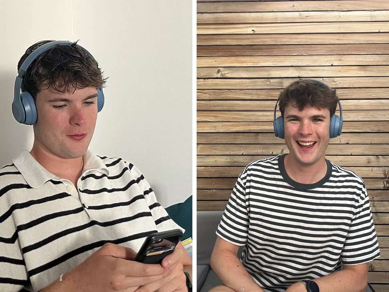 Young man wearing blue wireless headphones and a striped shirt, using a smartphone and smiling by a wooden wall