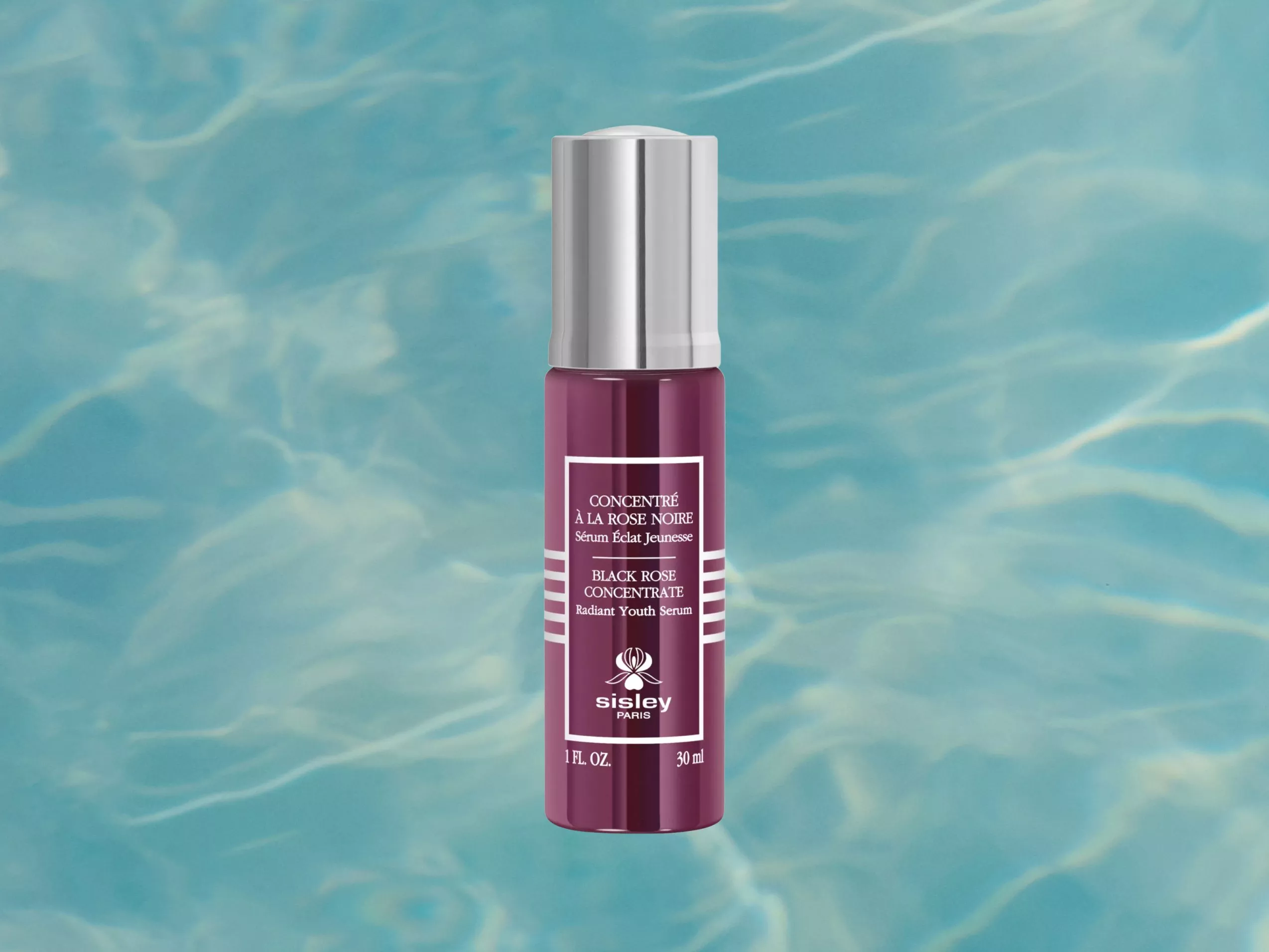 Sisley Paris Black Rose Concentrate Radiant Youth Serum bottle on blue water ripple background, 30 ml skincare product