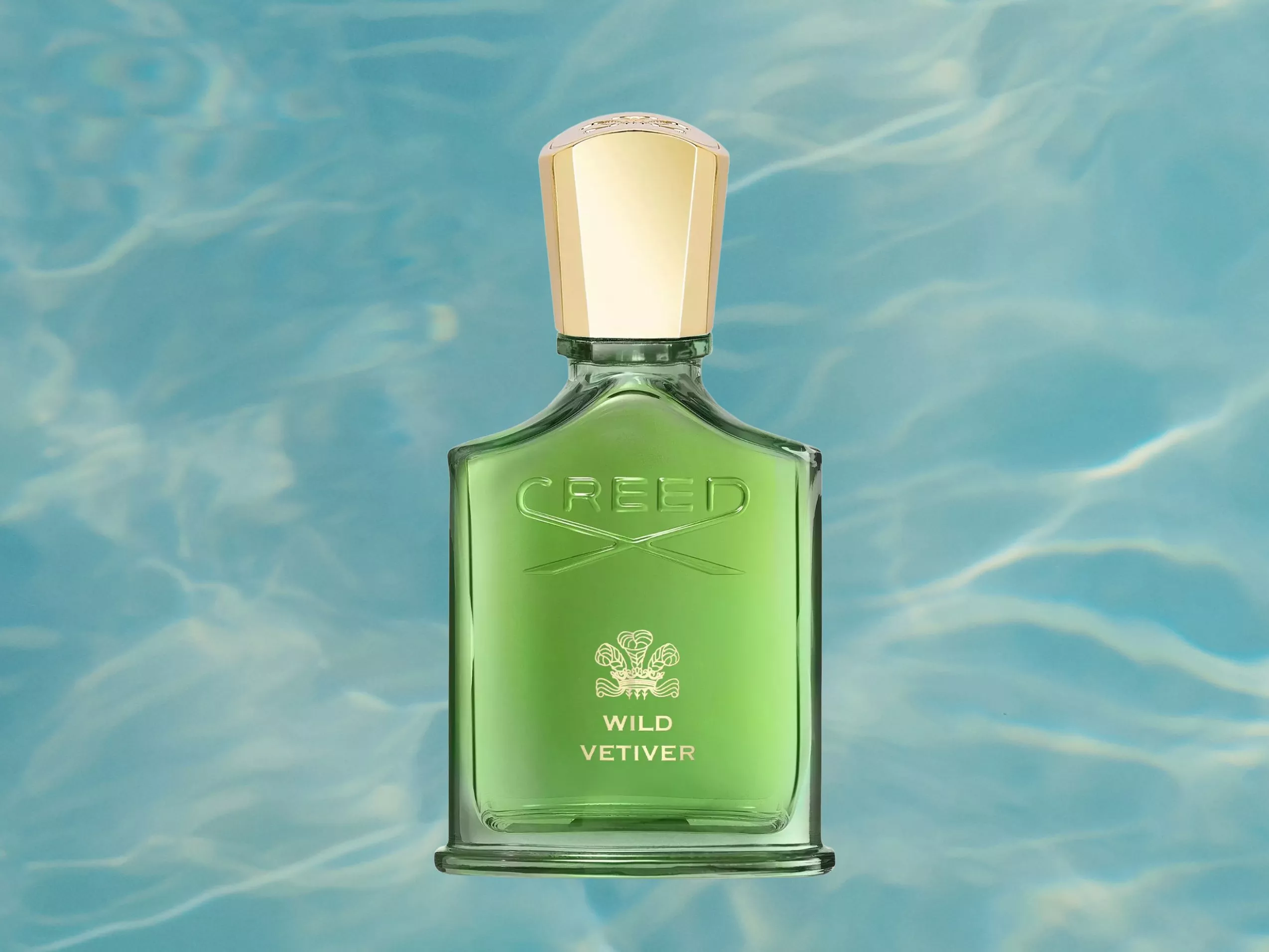 Creed Wild Vetiver green perfume bottle with gold cap on a blue water ripple background, luxury fragrance product shot