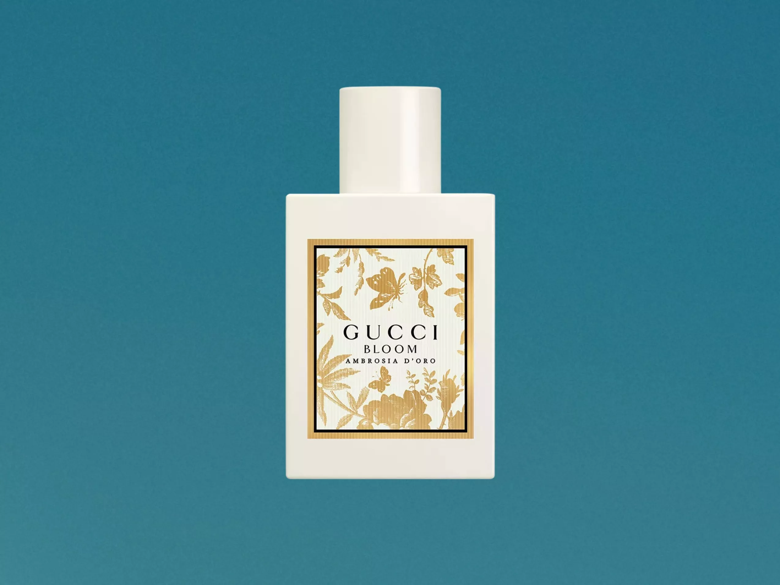 Gucci Bloom Ambrosia d’Oro perfume bottle with gold floral label on a teal background, luxury fragrance product photo