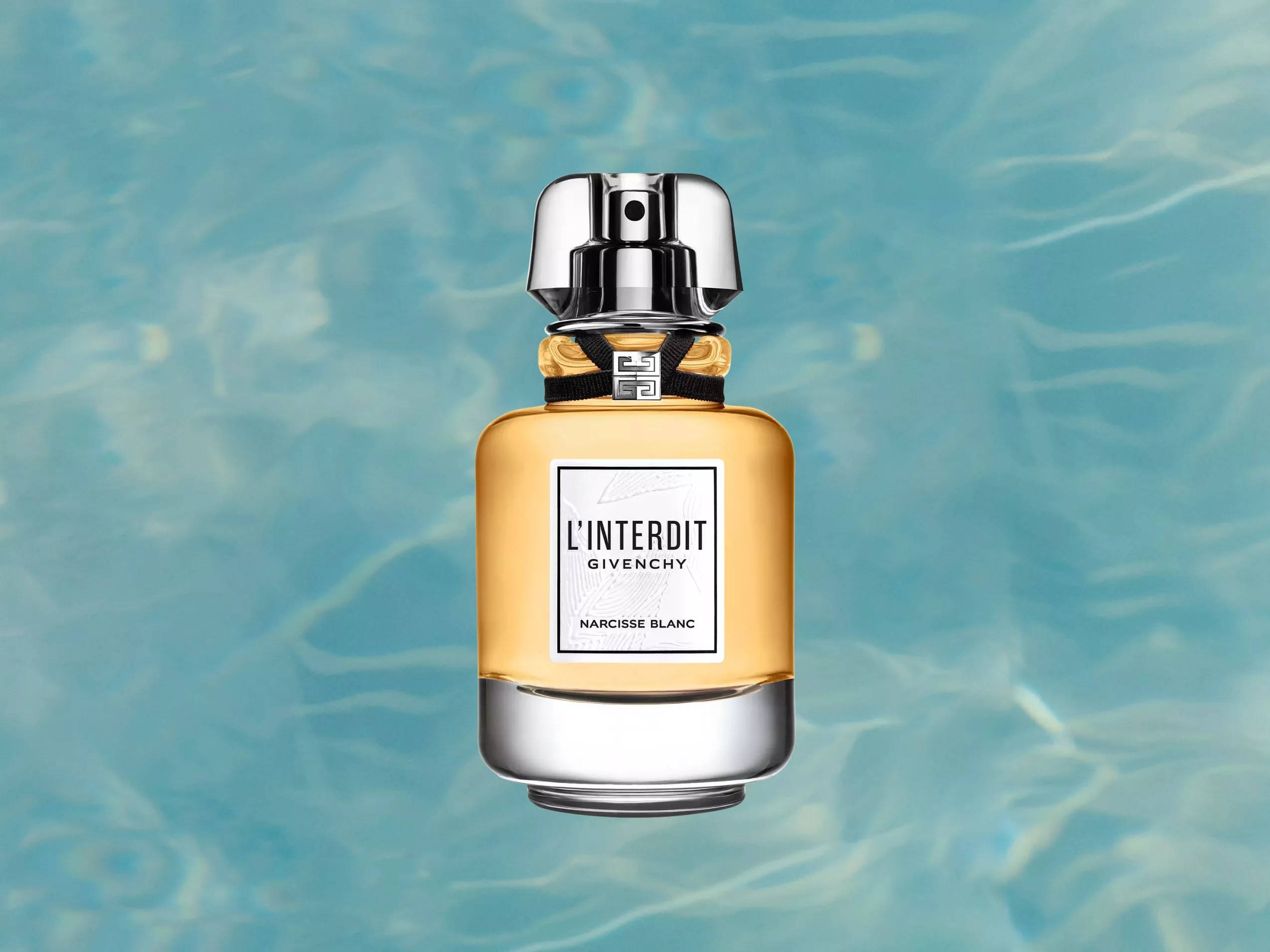 Givenchy L’Interdit Narcisse Blanc perfume bottle with golden fragrance and silver cap on blue water background