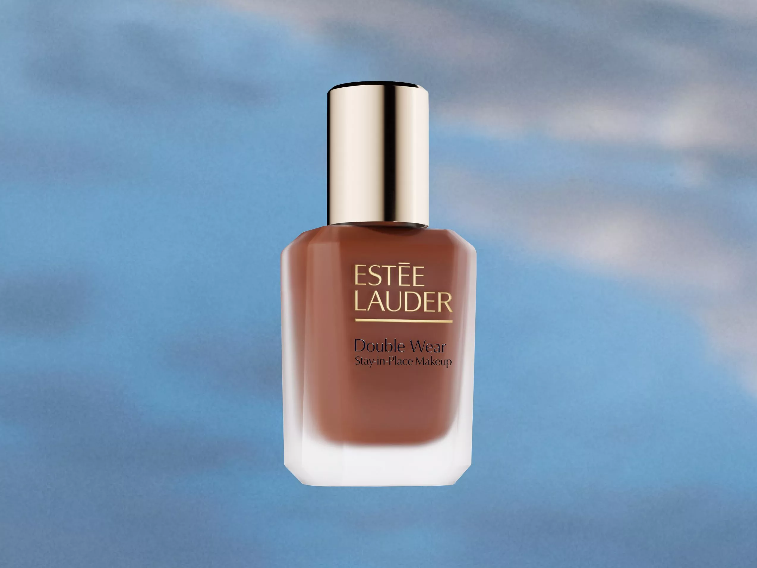 Estee Lauder Double Wear foundation bottle against a soft blue sky background, showcasing its sleek design.