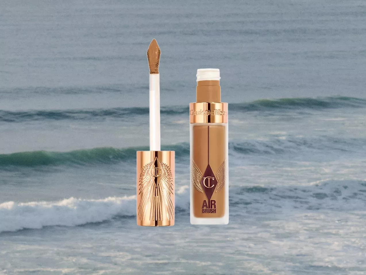 Charlotte Tilbury product against an ocean backdrop, featuring a luxurious concealer with a rose gold cap and applicator.