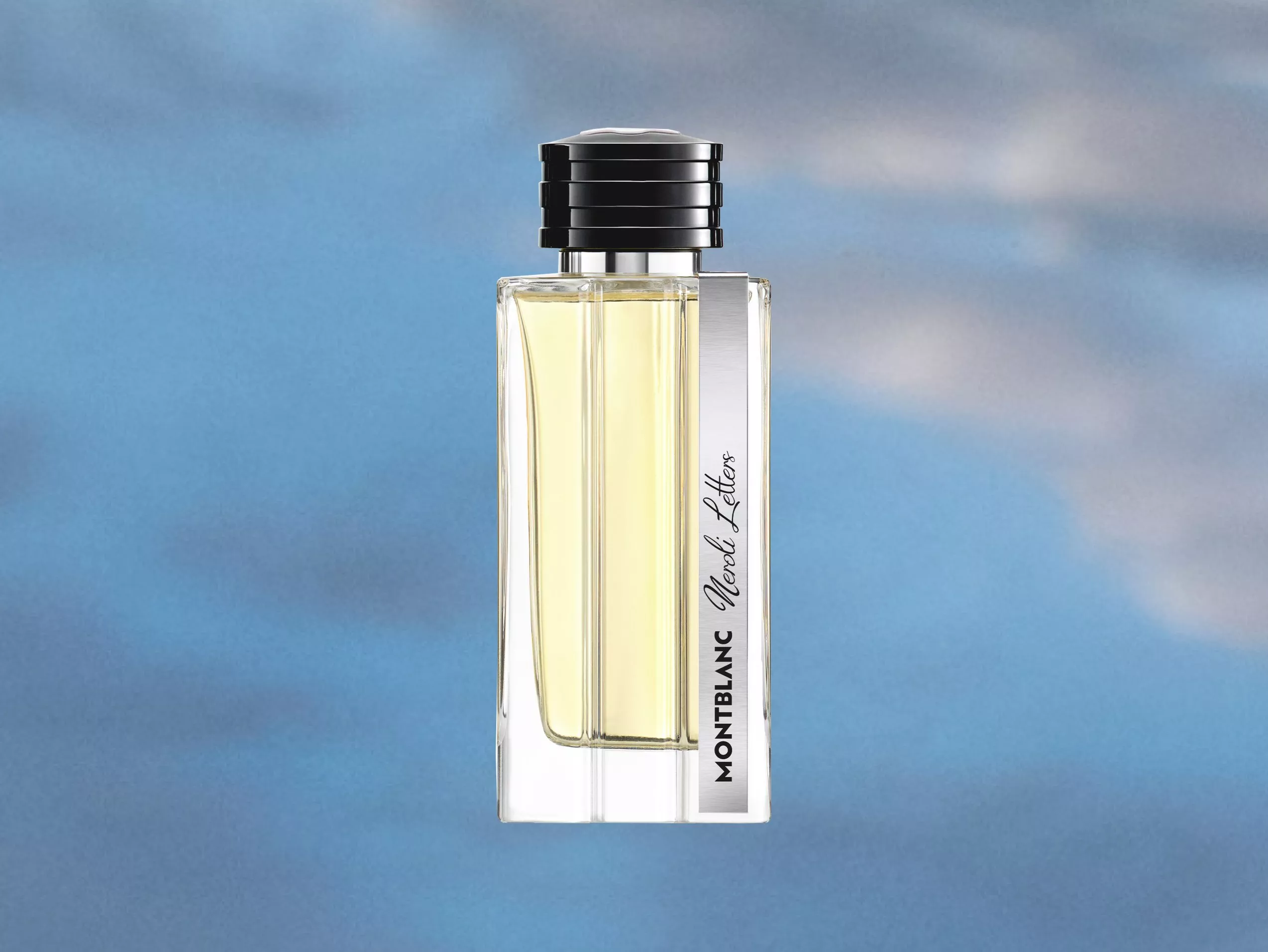 Clear glass bottle of Montblanc fragrance with a silver cap against a blue sky background.