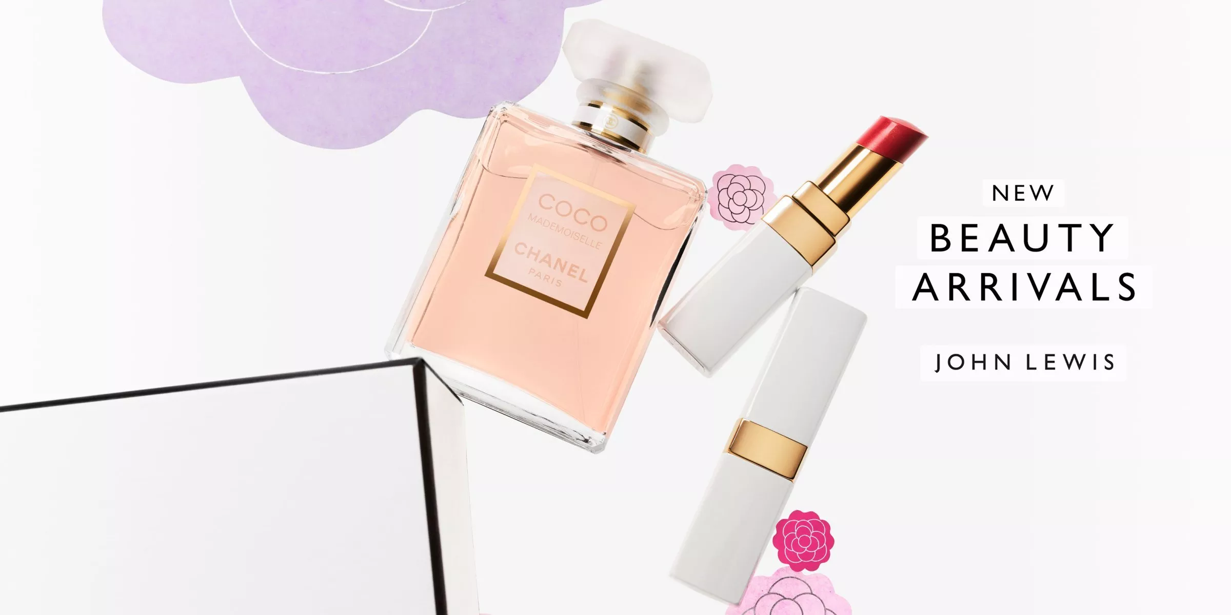 A bottle of Coco Mademoiselle Chanel falling off a box with red Chanel lipsticks, with flowers in the background