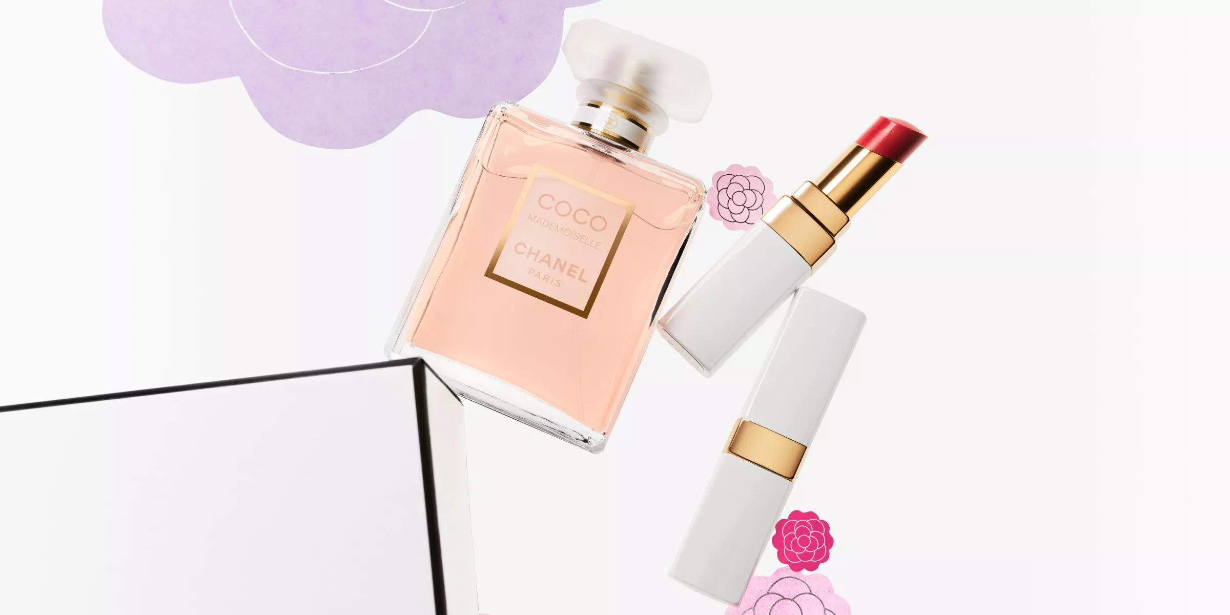 Perfume bottle and lipstick with floral accents on a white background, featuring elegant packaging.