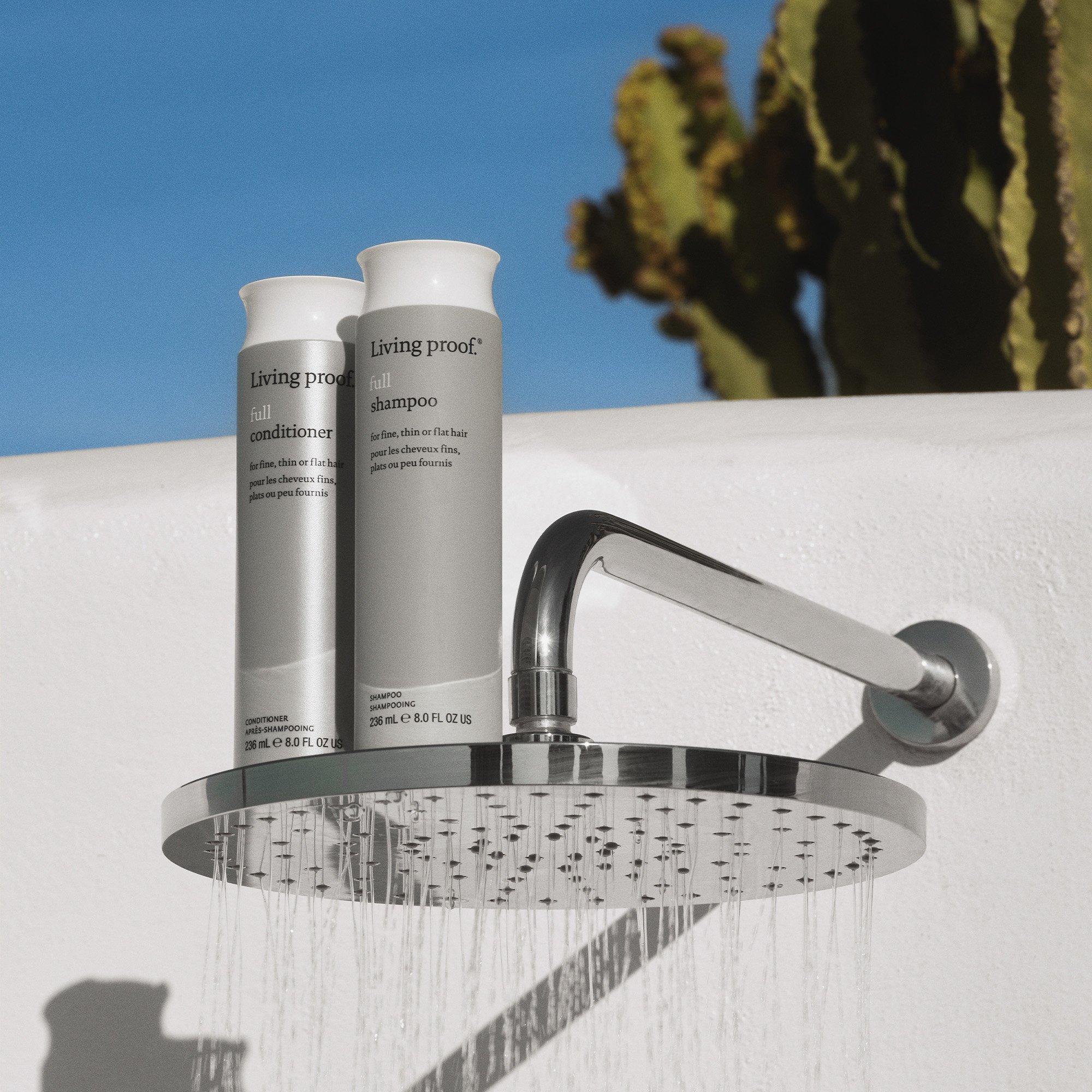 Living Proof shampoo and conditioner sitting on a large flat shower head.