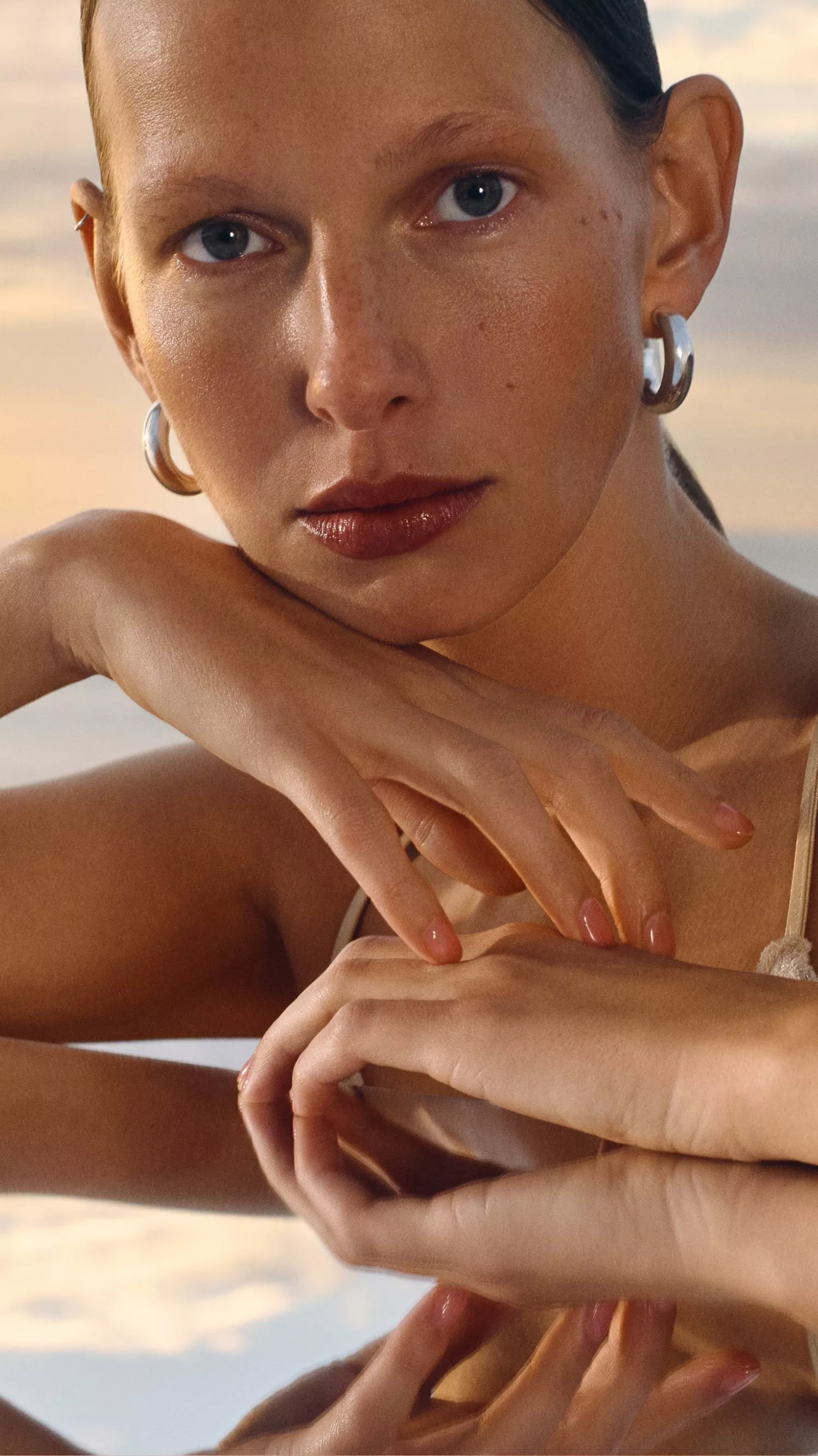 A serene sunset background with a person wearing eyecream and makeup