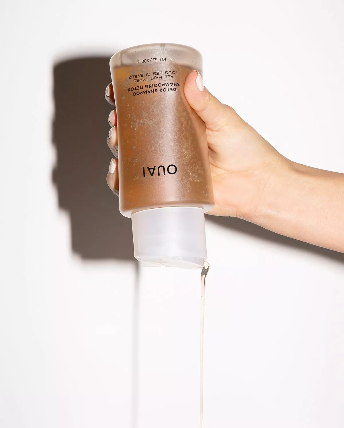 Woman pouring OUAI shampoo out of bottle