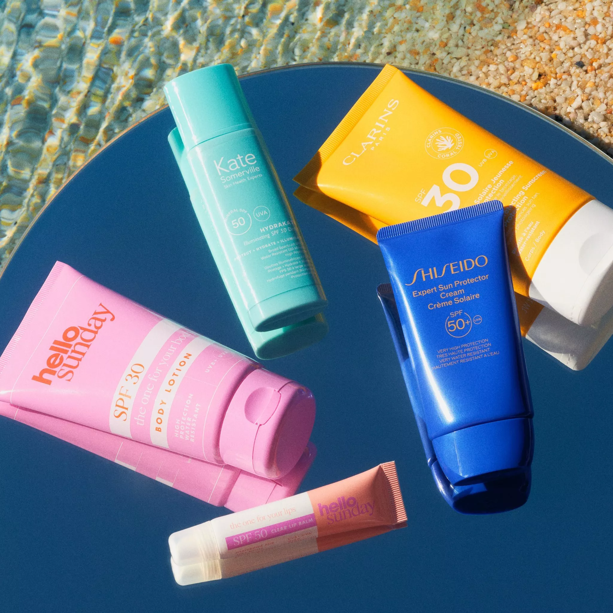 Colourful sunscreens on a mirror reflecting the sky by shimmering water.