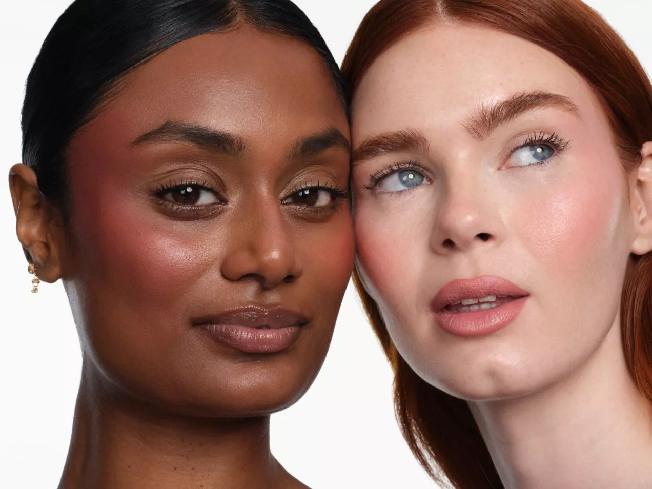 Close-up portrait of two women with dewy skin, blush and nude lipstick, showcasing natural makeup on white background