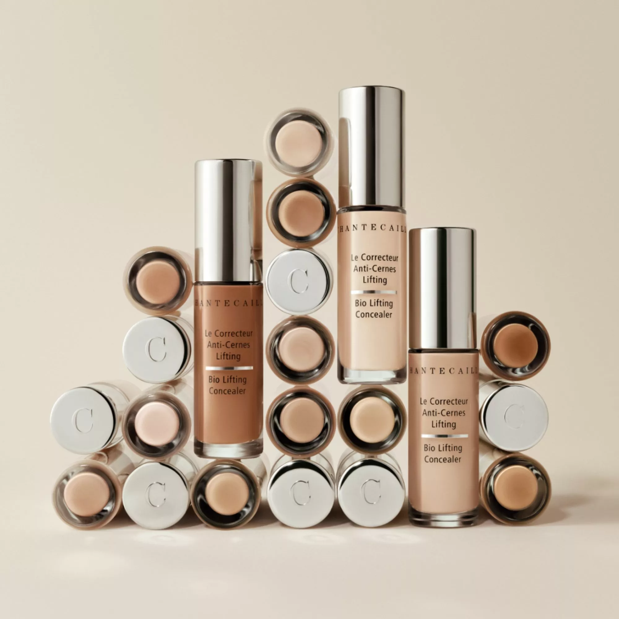 Chantecaille Bio Lifting Concealer tubes and caps stacked, showcasing multiple shades on a beige background