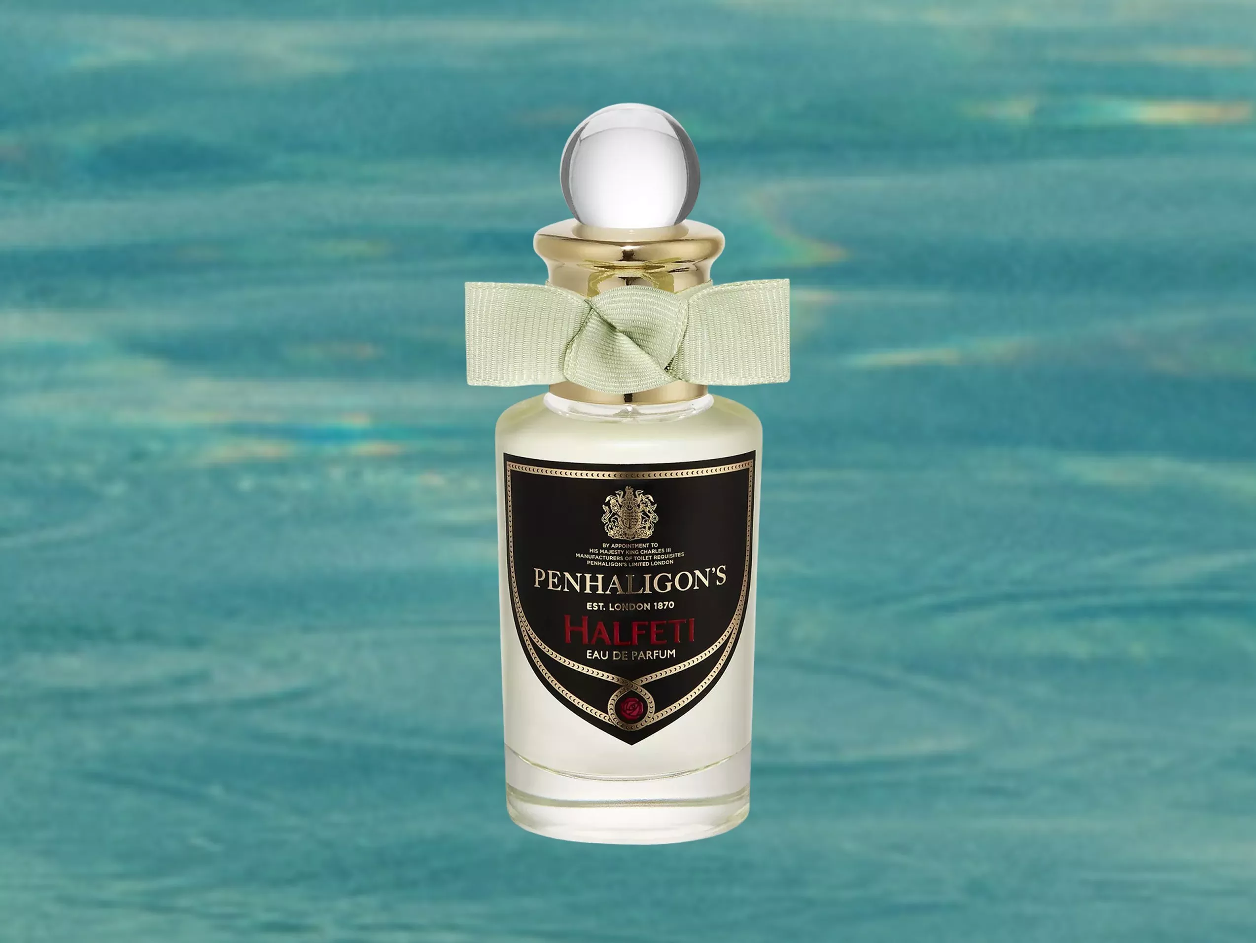 Penhaligon’s Halfeti eau de parfum bottle with gold cap and ribbon, photographed on a swimming pool water backdrop