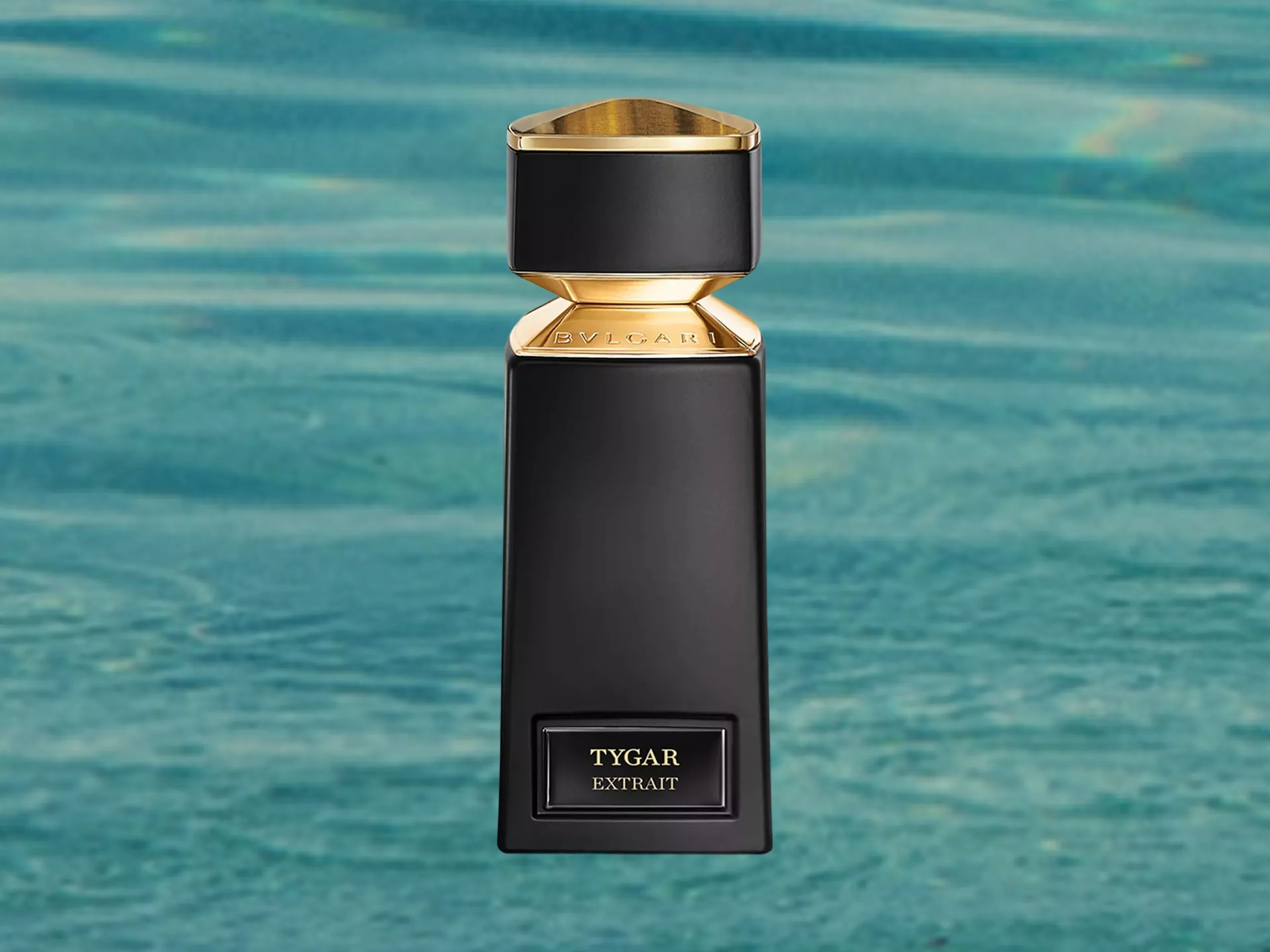 Bvlgari Tygar Extrait perfume bottle in black and gold, on turquoise pool backdrop