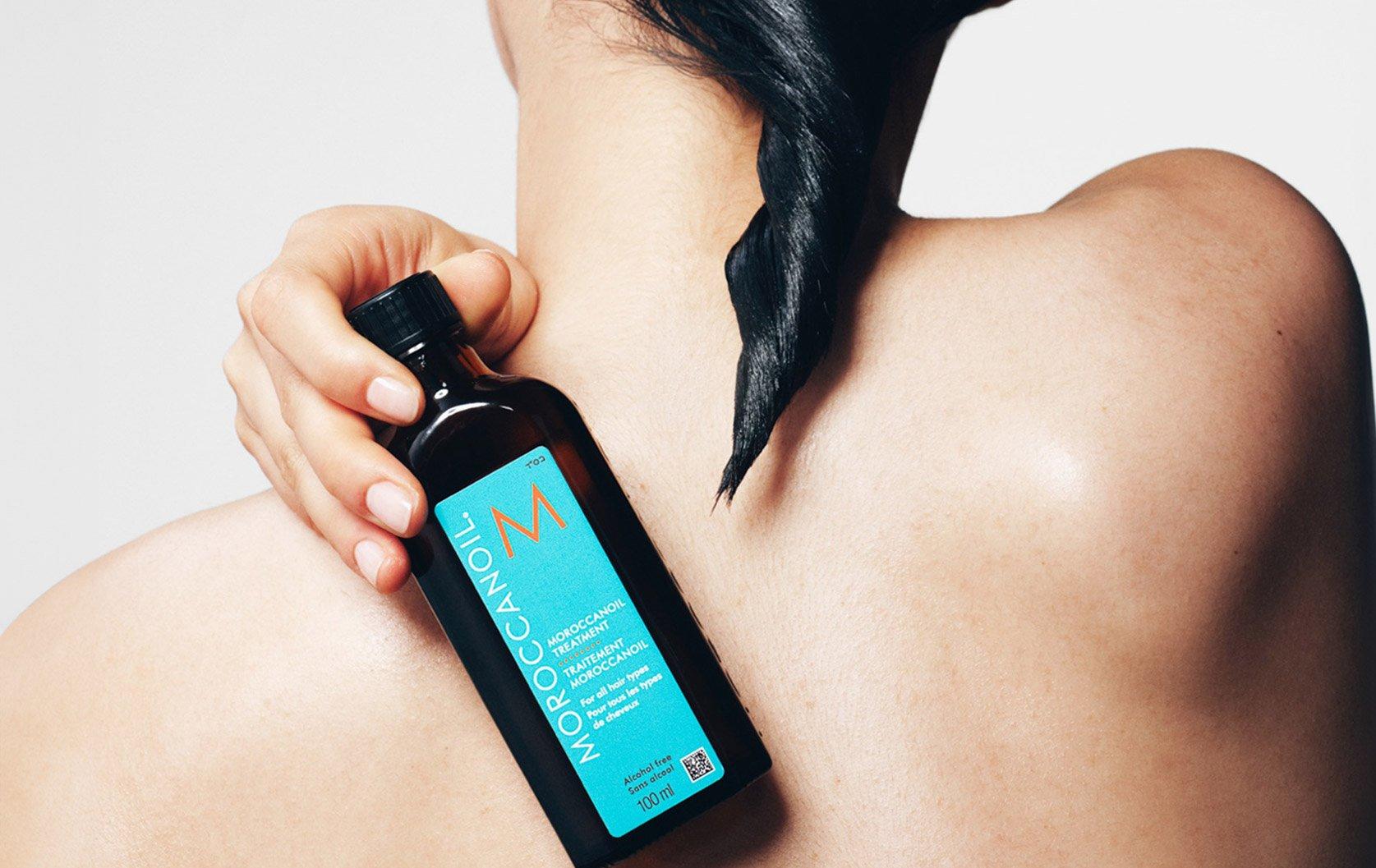 Woman with wet hair holding Moroccanoil treatment