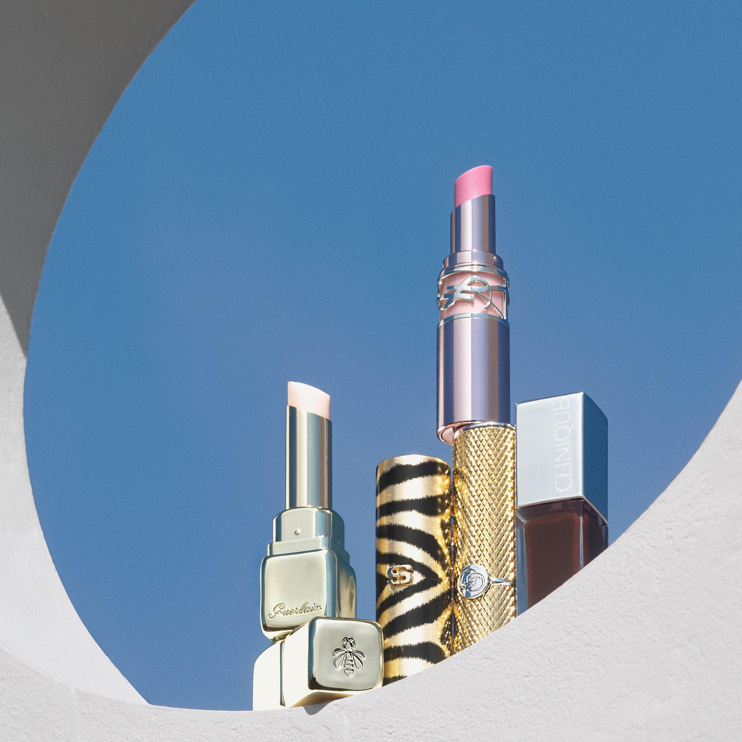 Range of lipsticks stacked on a white ledge against a blue sky
