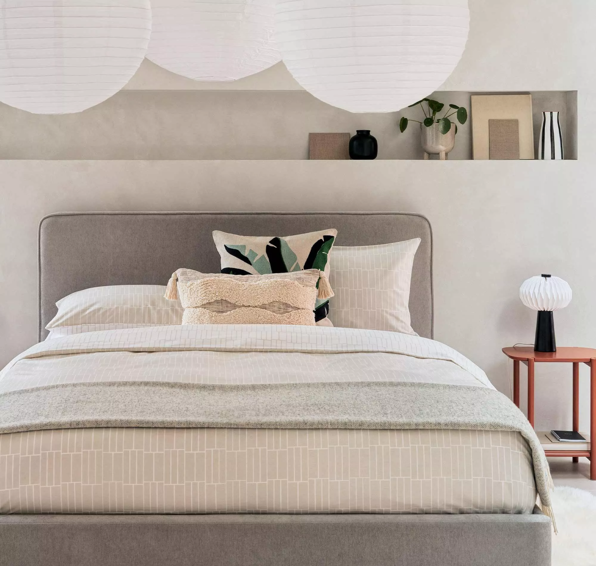 White wooden bed frame with deep quilted mattress and pillows in a bright modern bedroom by a window