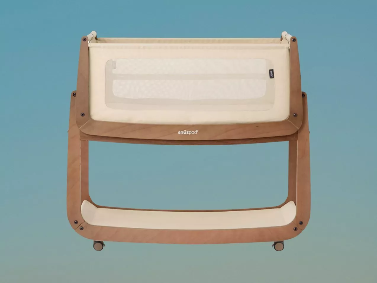 Wooden baby bedside crib with cream fabric and mesh side panel, compact co-sleeper bassinet on wheels