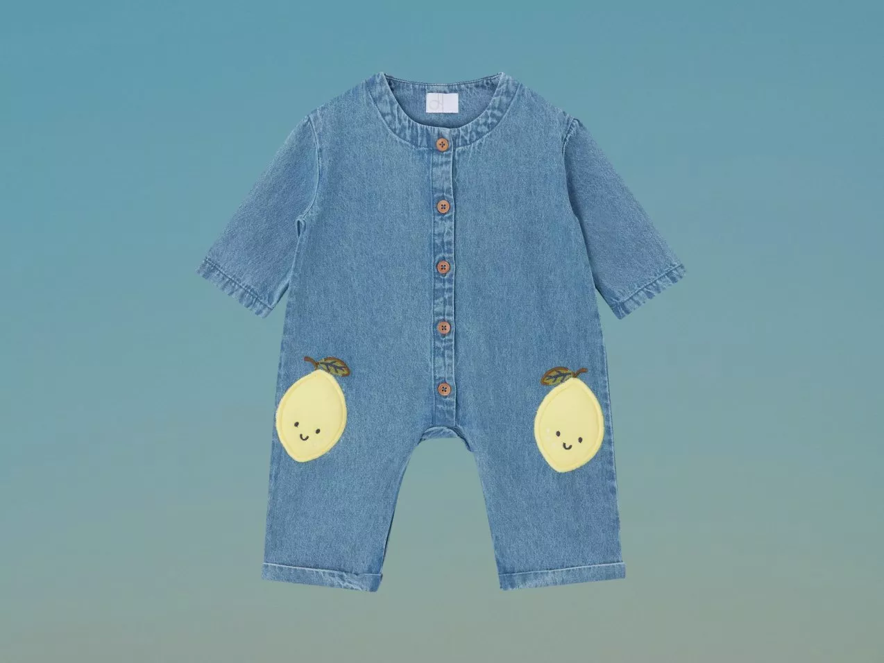 Baby denim romper with front buttons, short sleeves and cute lemon patch pockets, laid flat on white background
