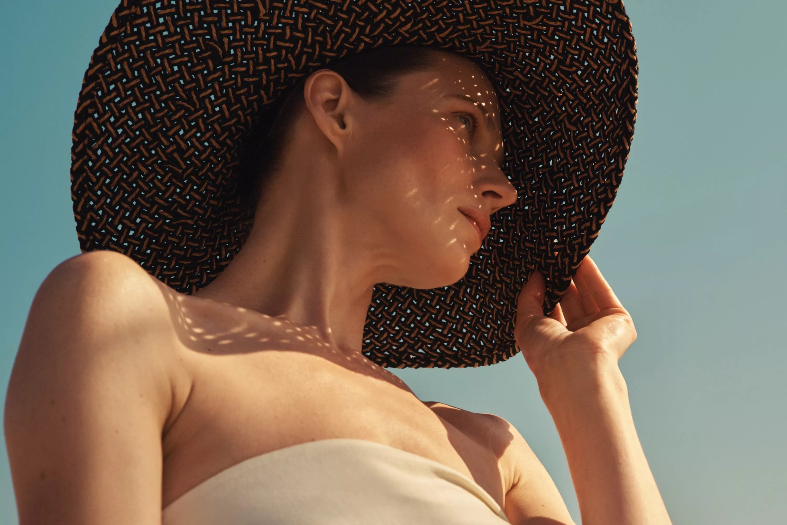 women holding a sunhat with her hand
